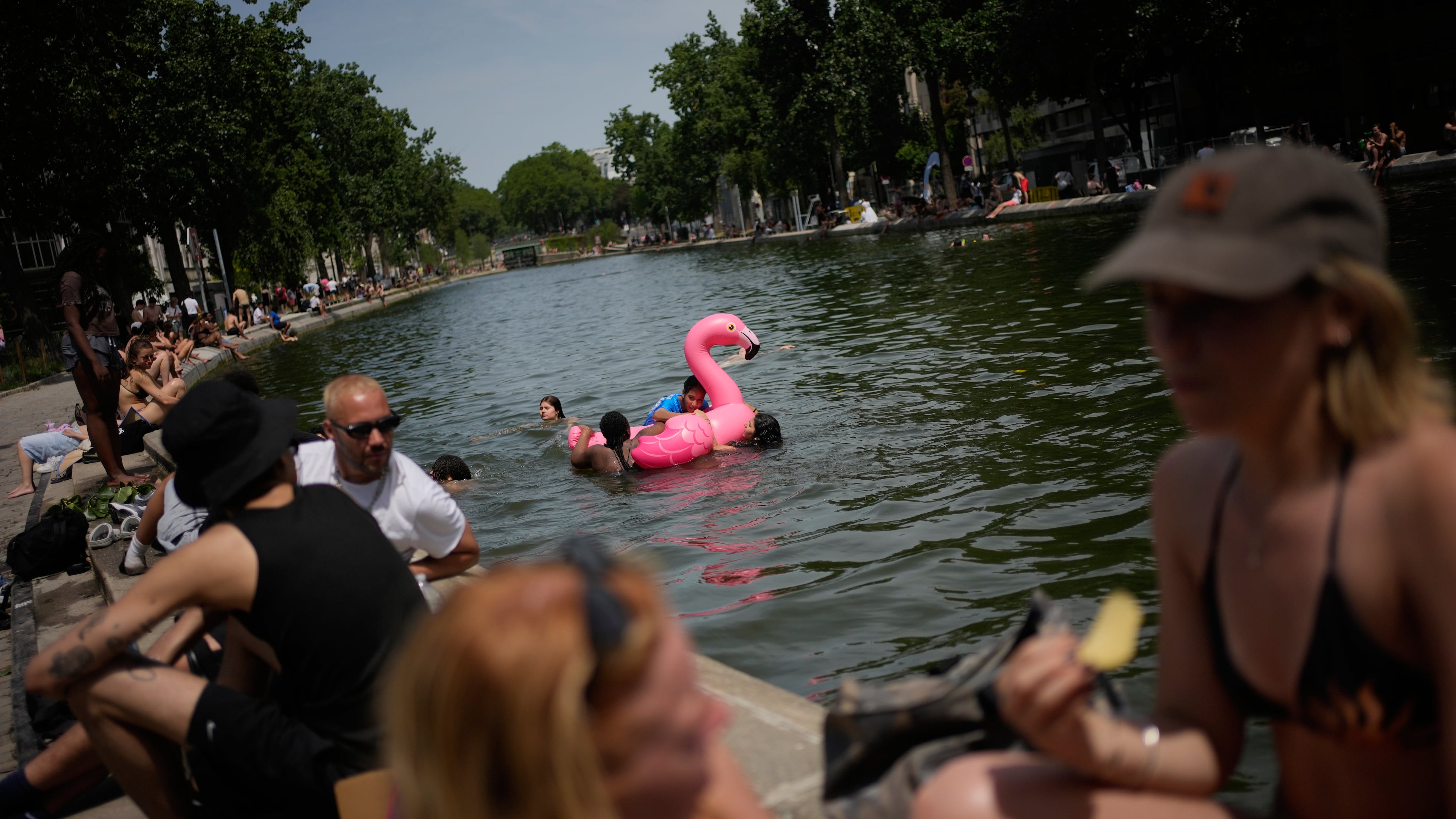 Parisians bath in the Canal Saint-Martin in Paris, as the national weather service, Meteo France, placed 54 departments, about half the country, under a red heat wave alert, Tuesday, June 23, 2026. (AP Photo/Christophe Ena )