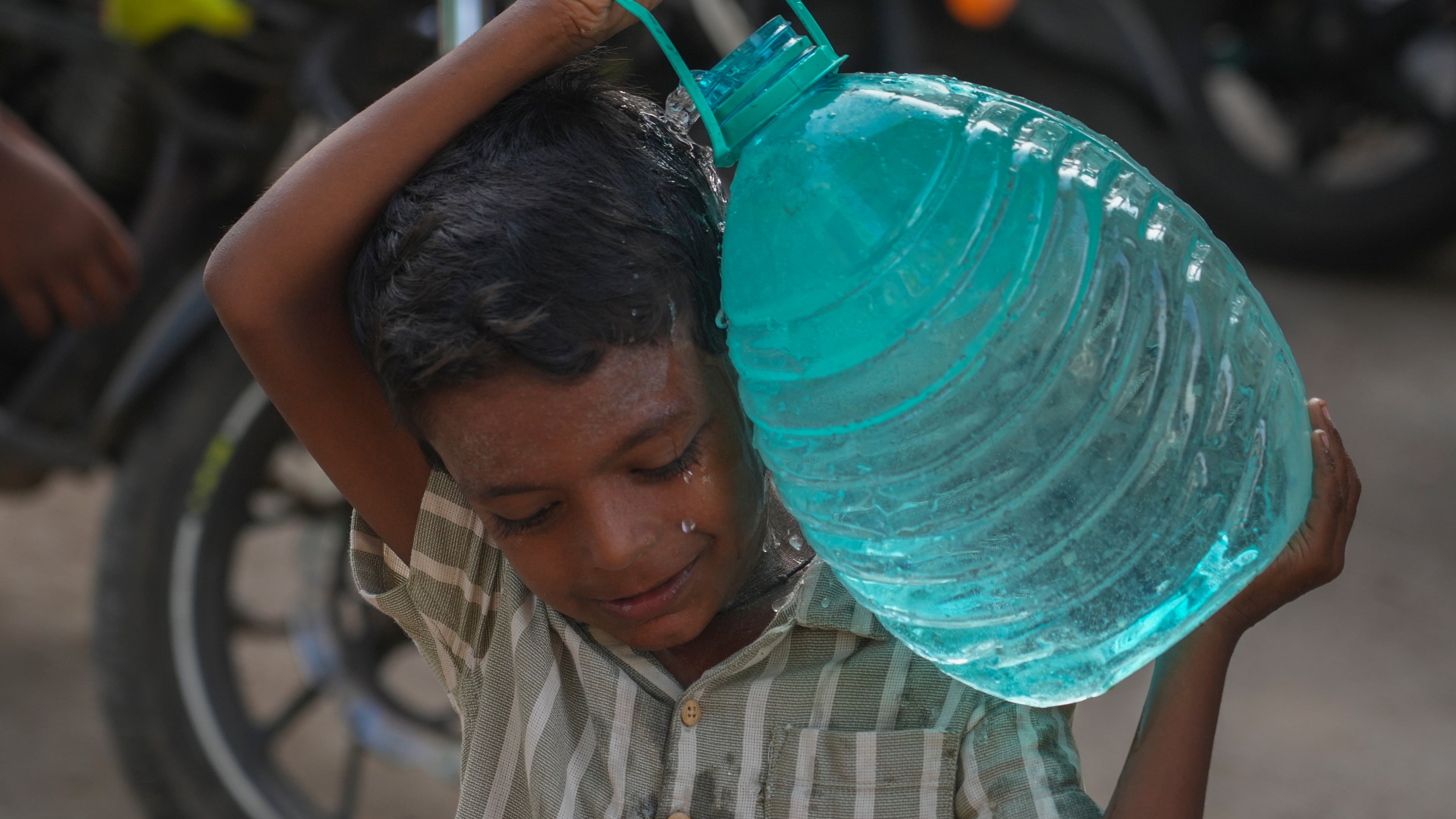 A boy carries a water can which he collect from a public tap in Mumbai, India, Saturday, June 20, 2026. (AP Photo/Rafiq Maqbool)