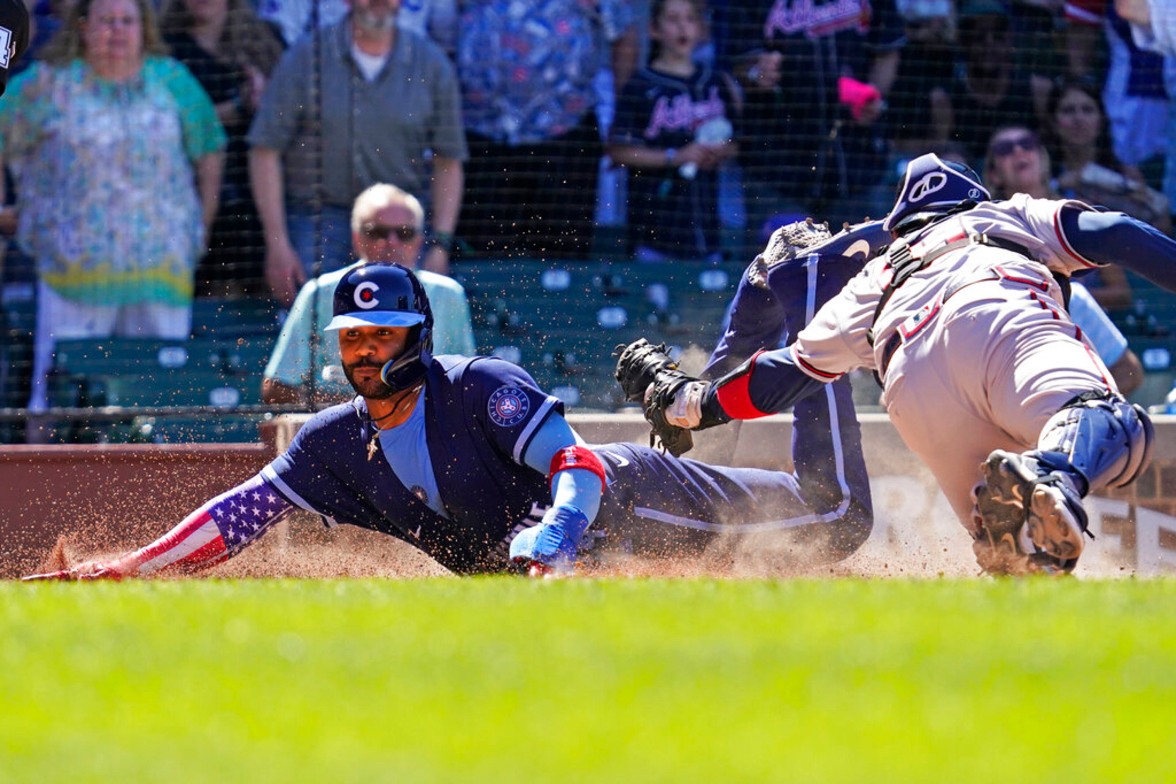 Chicago Cubs' Jonathan Villar, left, scores on a sacrifice fly by Christopher Morel as Atlanta Braves catcher Travis d'Arnaud applies a late tag during the eighth inning of a baseball game in Chicago, Friday, June 17, 2022. (AP Photo/Nam Y. Huh)