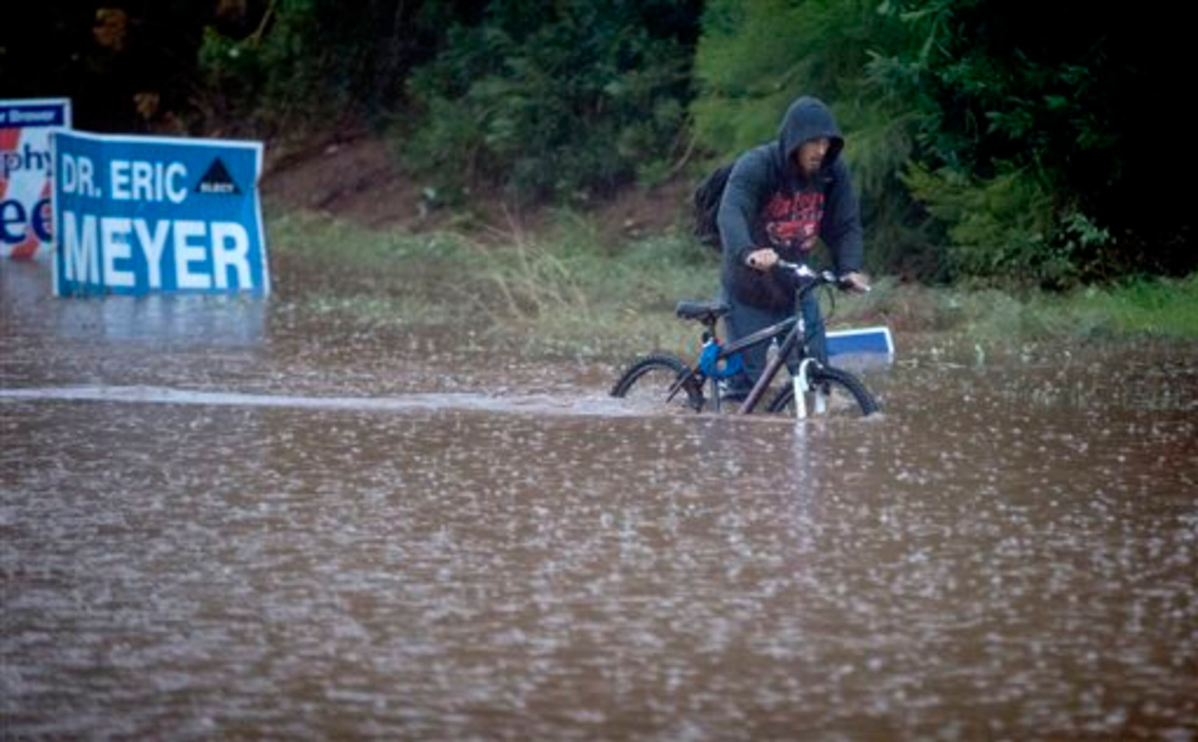Construction worker Jason Haight Jr. makes his way back home, through high water at 54th Street and Camelback Avenue, Monday, Sept. 8, 2014, in Phoenix. Haight and his father rode to their construction site only to find work canceled for the day. (AP Photo/The Arizona Republic, Charlie Leight)