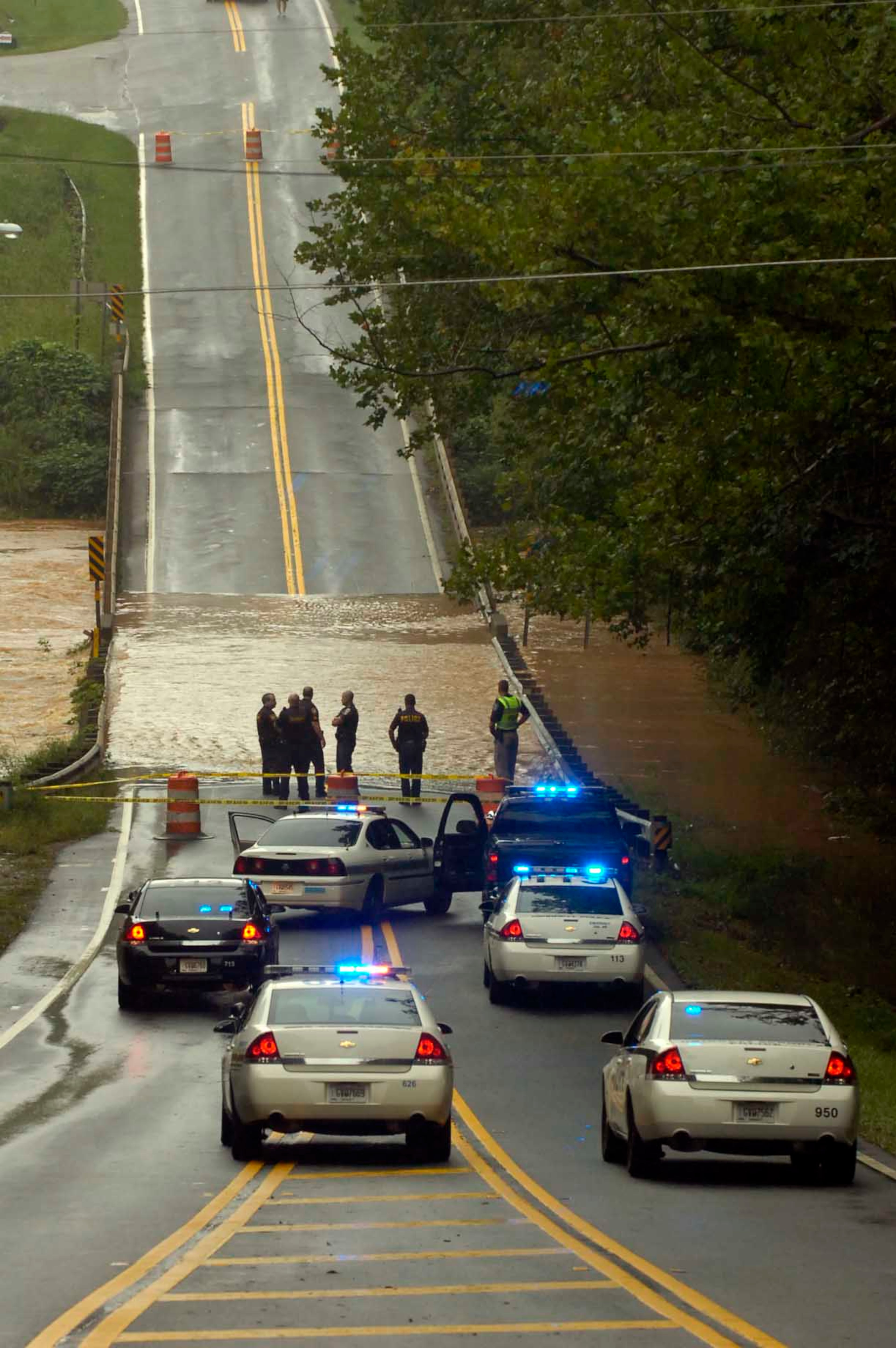 090921--LILBURN-- Gwinnett Police officers and Sheriffs Department deputies block the bridge across the Yellow River on Killian Hill Road Monday morning. The normally placid Yellow River was turned into a raging flood that overflowed its banks during torrential rains late Sunday night. Flooding was widespread in several counties in metro Atlanta Monday, with more rain in the forecast. Kent D. Johnson, kdjohnson@ajc.com
