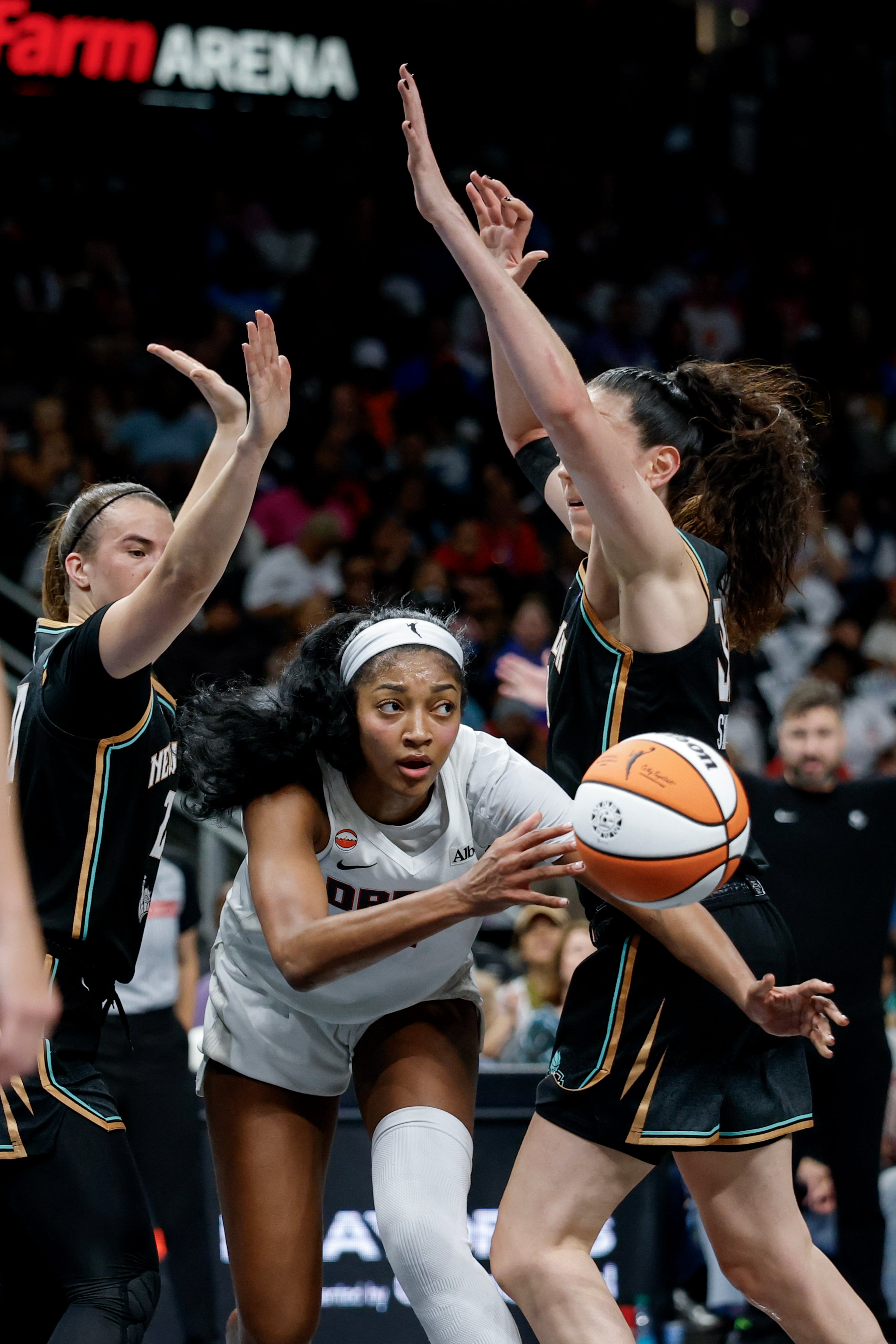 Atlanta Dream forward Angel Reese, center, passes between New York Liberty guard Sabrina Ionescu, left, and forward Breanna Stewart, right, during the first half of a WNBA semifinal playoff game 1 between the Atlanta Dream and the New York Liberty, Sunday, Oct. 4, 2026, in Atlanta. (Erik S. Lesser for the AJC)
