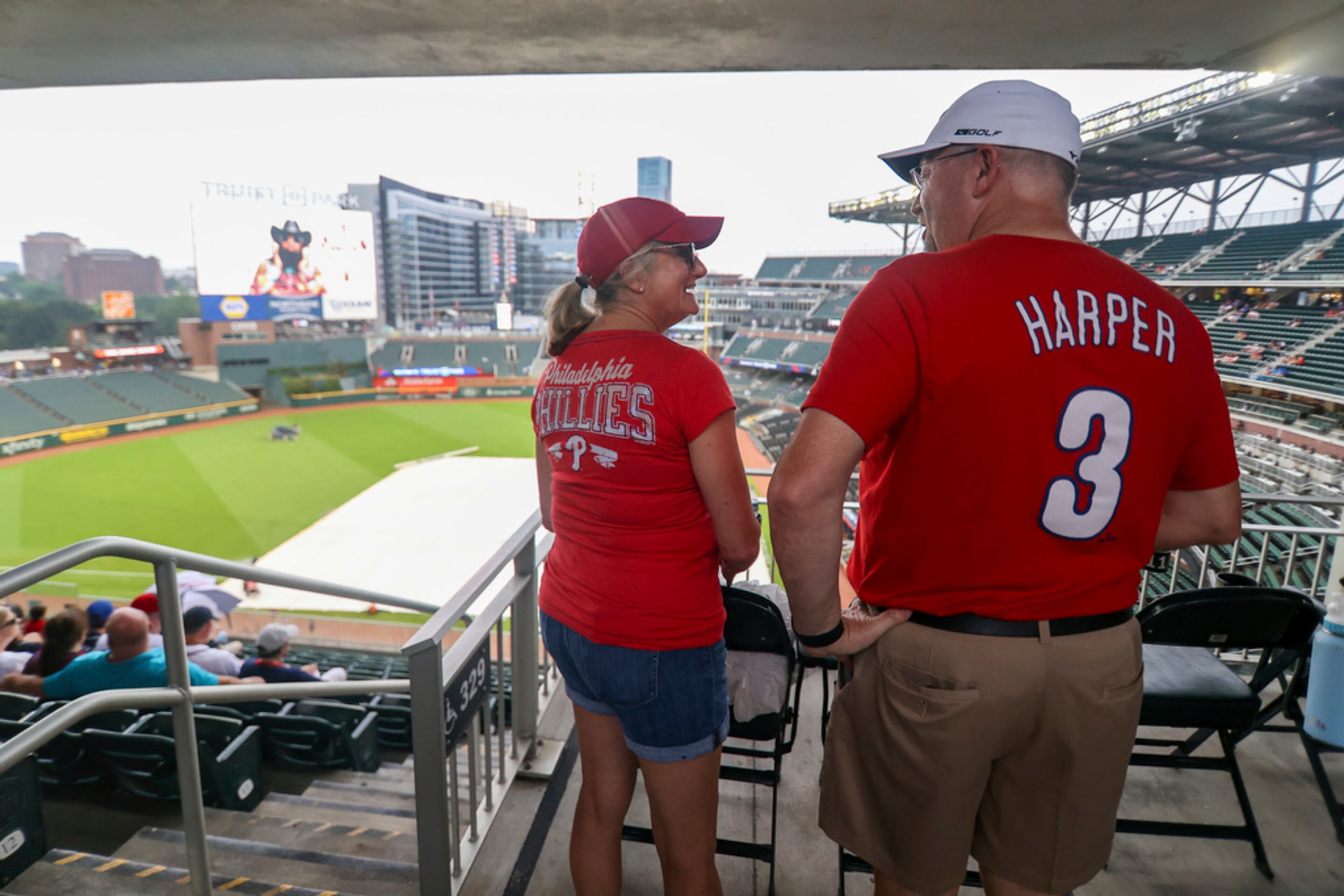 Philadelphia Phillies' fans talk in the stands as the tarp covers the field before a baseball game against the Atlanta Braves Saturday, July 6, 2024, in Atlanta. (AP Photo/Brett Davis)