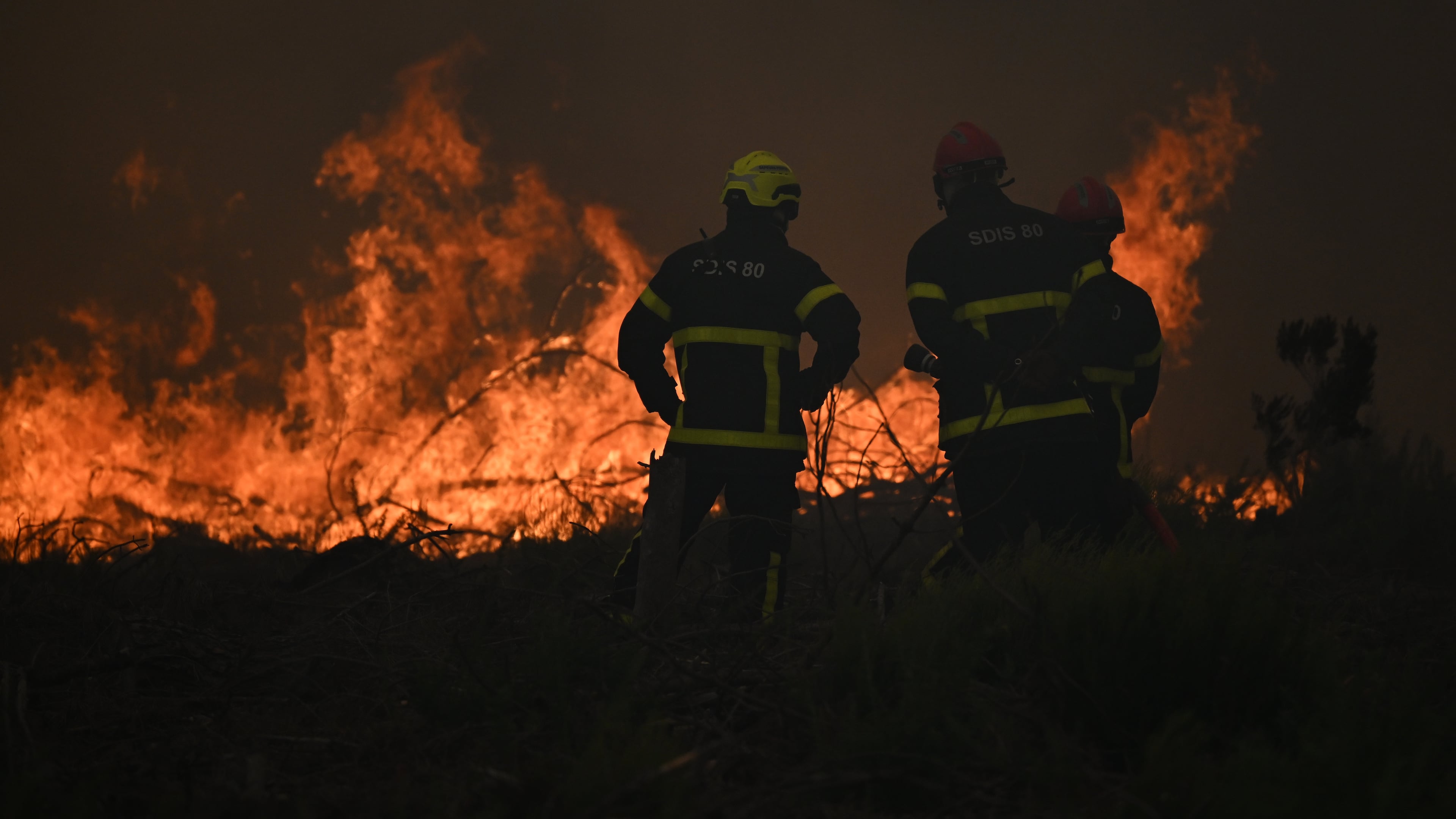 Firefighters spray water in a burning forest near Lacanau, southwestern France, Saturday, July 25, 2026. (AP Photo/Emma Da Silva)