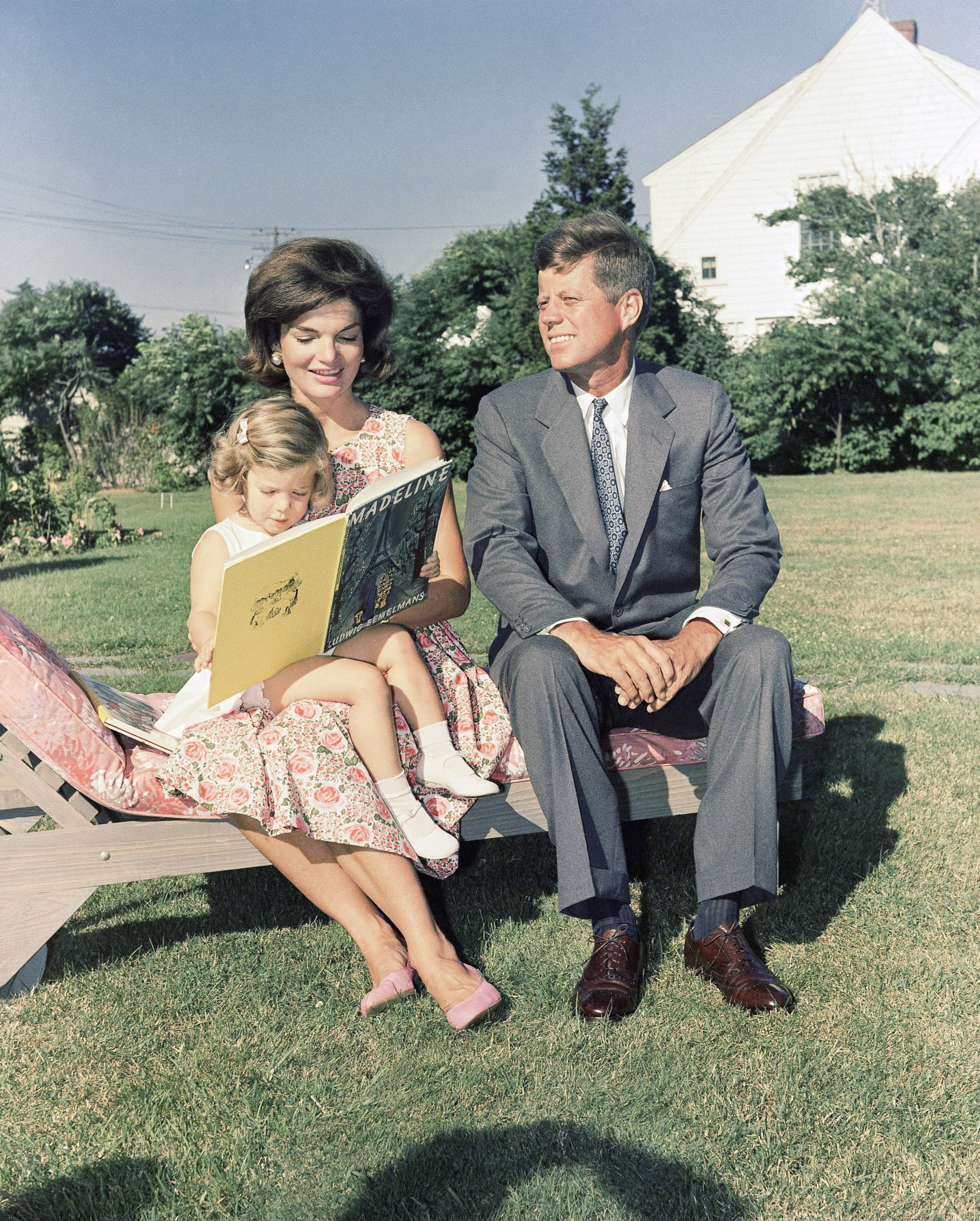 Sen. John F. Kennedy (D-Mass.) sits with wife, Jacqueline, who reads to their daughter, Caroline, at Hyannis Port, Mass. (AP Photo)