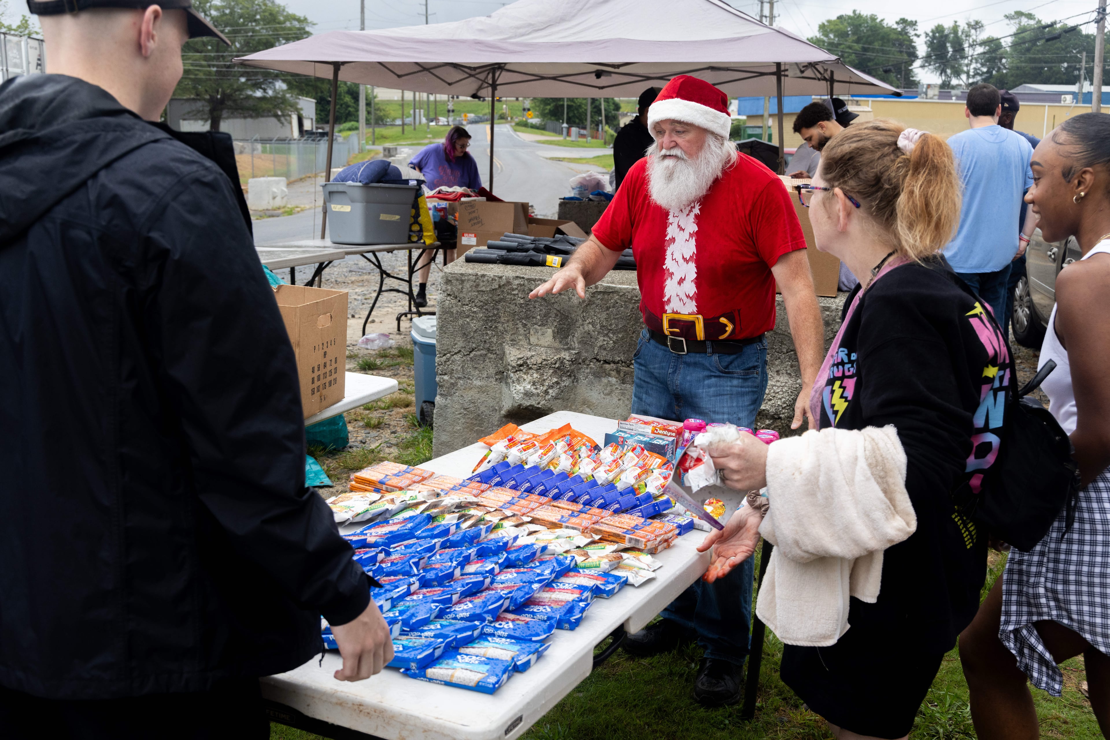 Randy Smith (center, in red) directs Santa for the Homeless volunteers as they set out food tables near a homeless encampment in Gainesville. "Santa Randy" leads the group, comprised of members from 10 different churches, providing much-needed supplies to the estimated 104 people who live at the encampment on the first Saturday of the month. (Phil Skinner for the AJC)