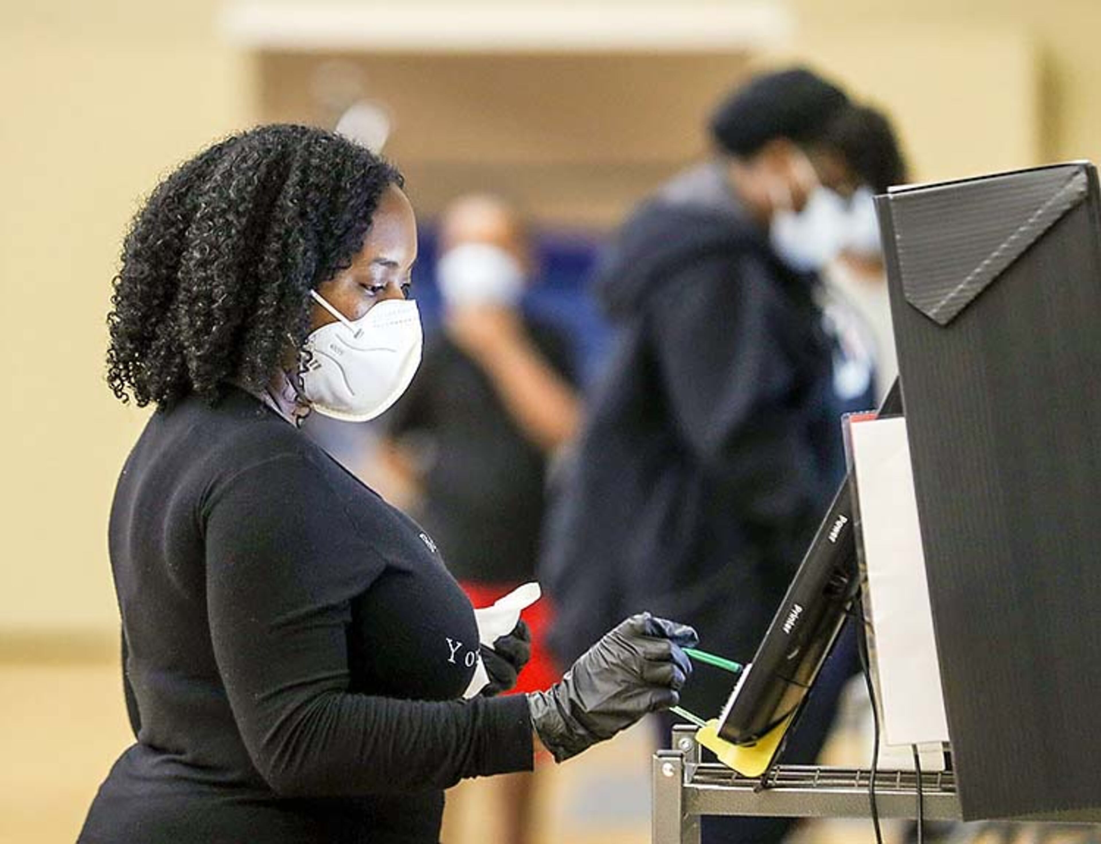 LaVonya Tensley of Smyrna wears gloves and a face mask while casting her vote at the Smyrna Community Center during the Georgia Primary, Tuesday, June 9, 2020. Voters were given the opportunity to use a stylus pen for the voting machines.