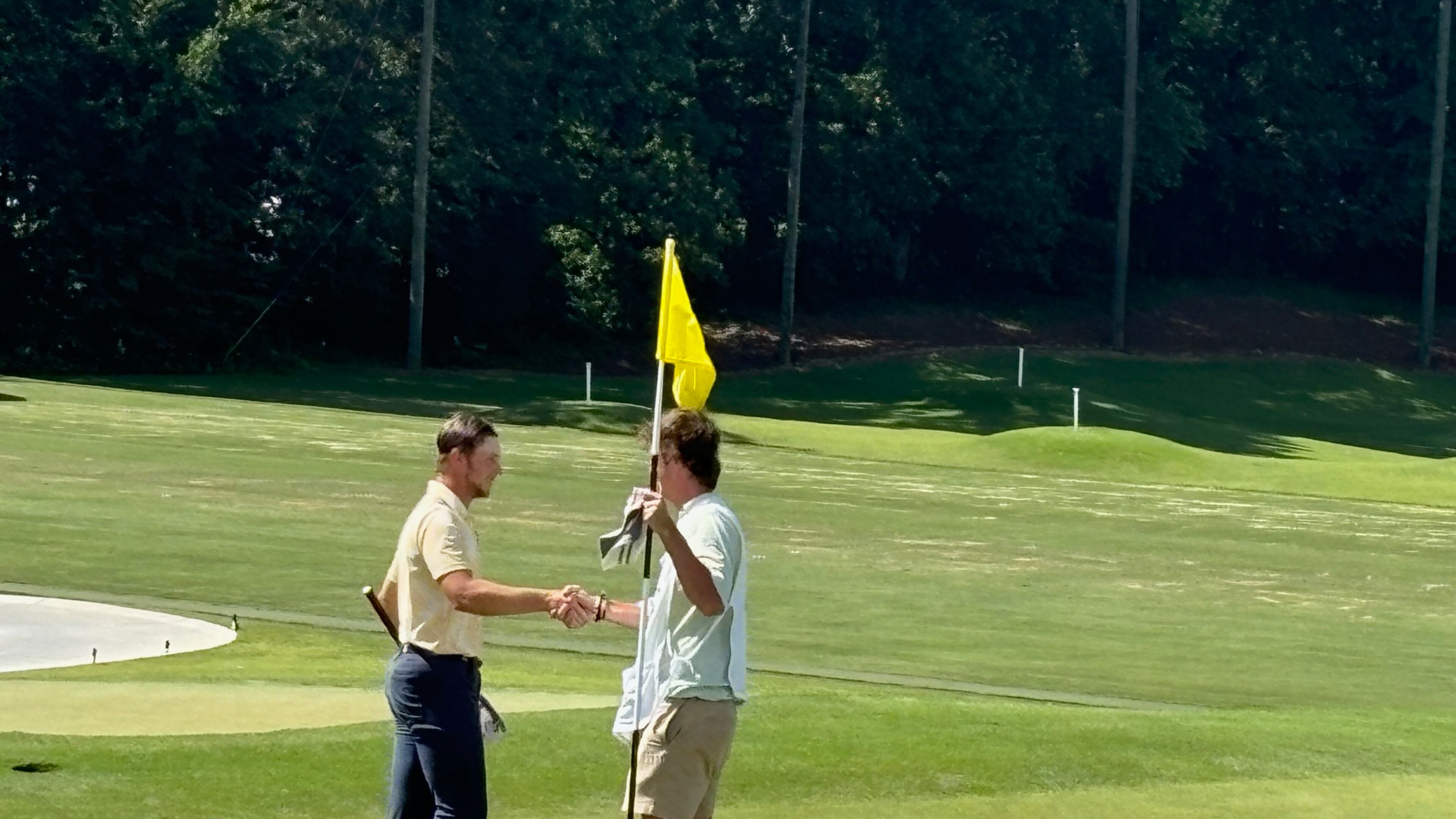 Garrett Engle (L) accepts congratulations from his opponent's caddie after tapping in on the 18th hole Engle, who plays at Tennessee-Chattanooga, won by shots at Druid Hills Golf Club, June 8, 2024.