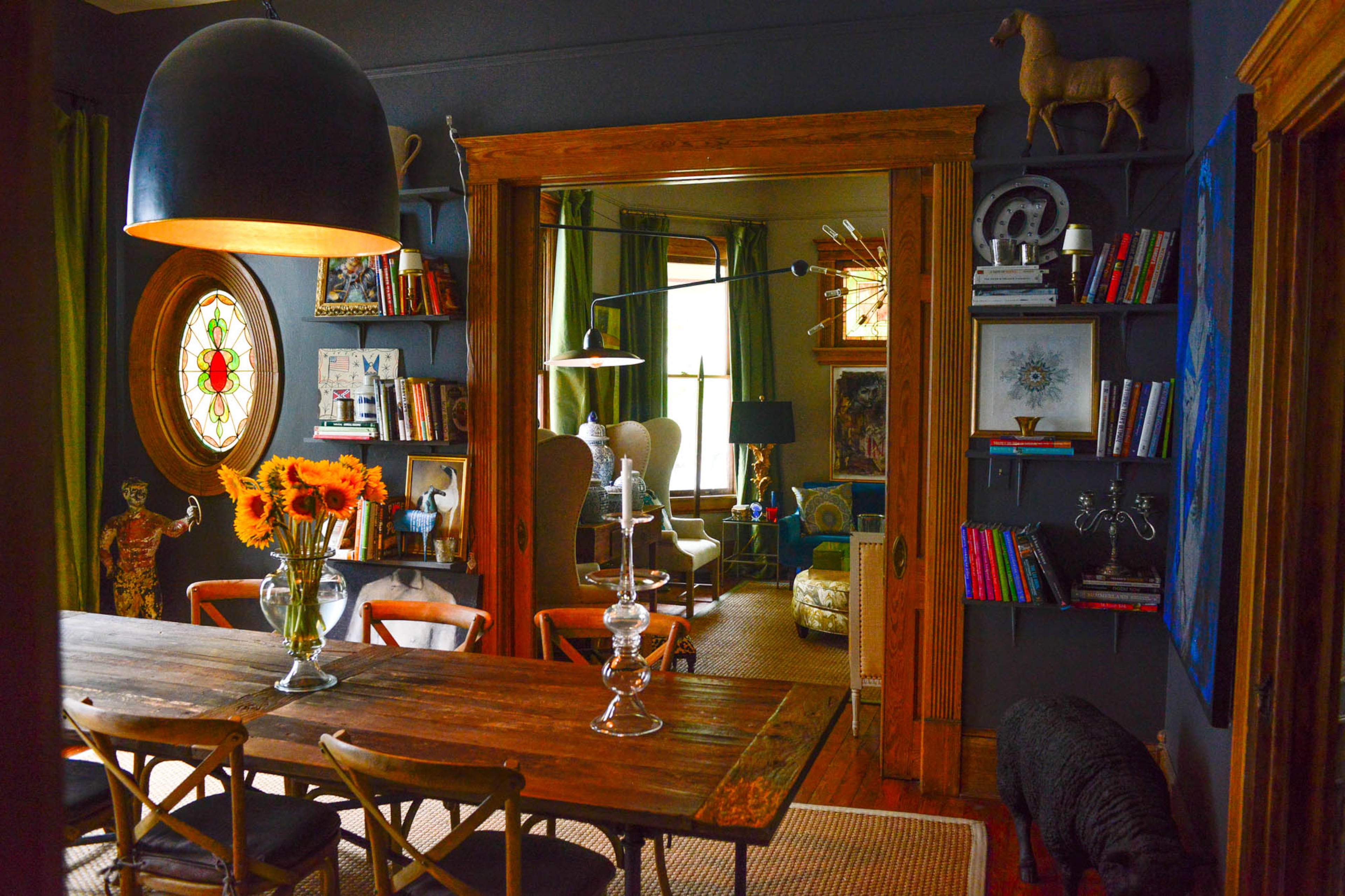 Resler says he loves the chic look of the industrial pendant juxtaposed with the farm-style table from RH in his dining room. The stained glass windows are believed to be original to the home.