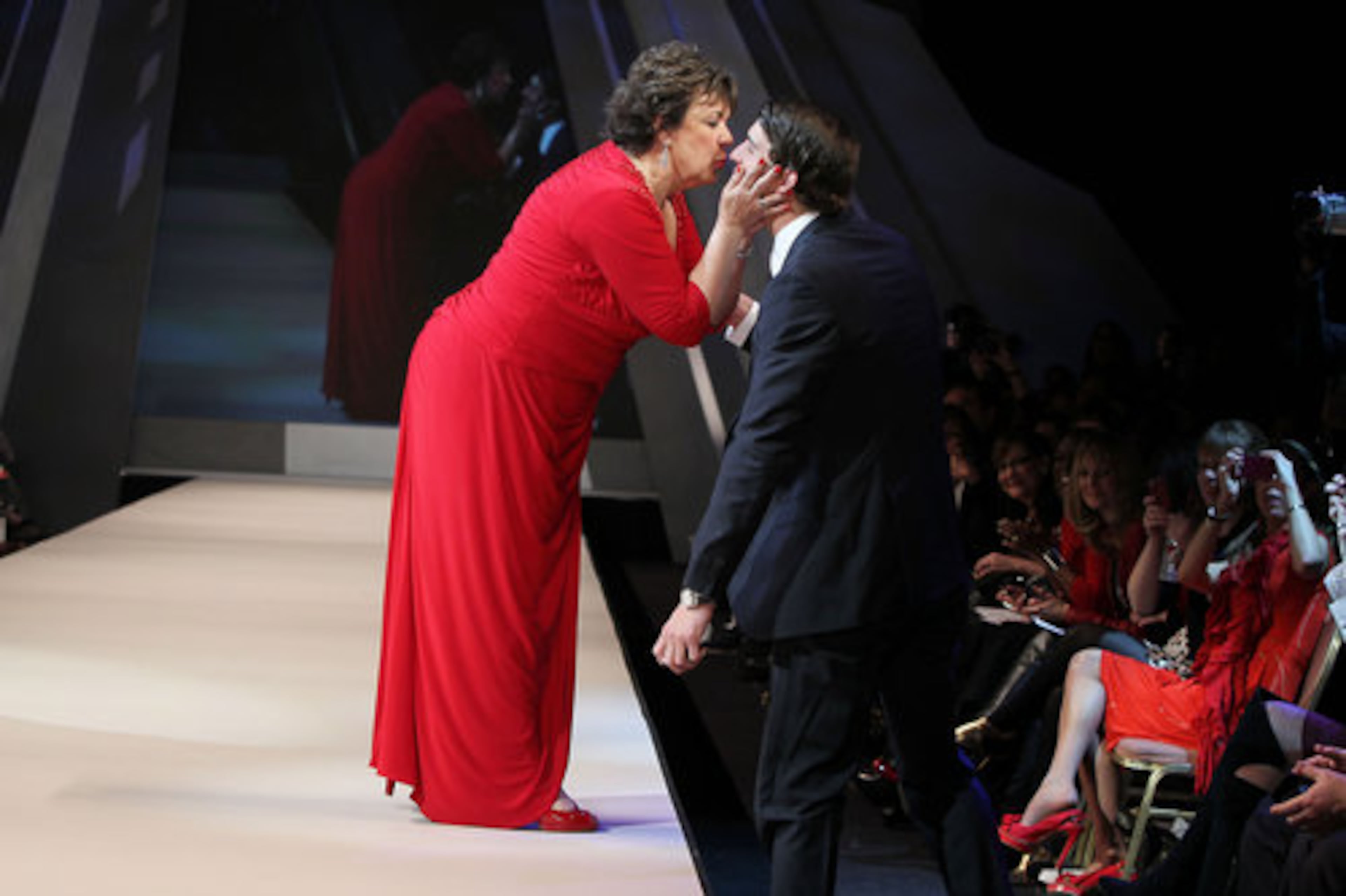Olympic gold medal swimmer Michael Phelps gets a kiss from his mother Debbie Phelps, who paused on the runway to greet her son as she modeled Adrianna Papell.