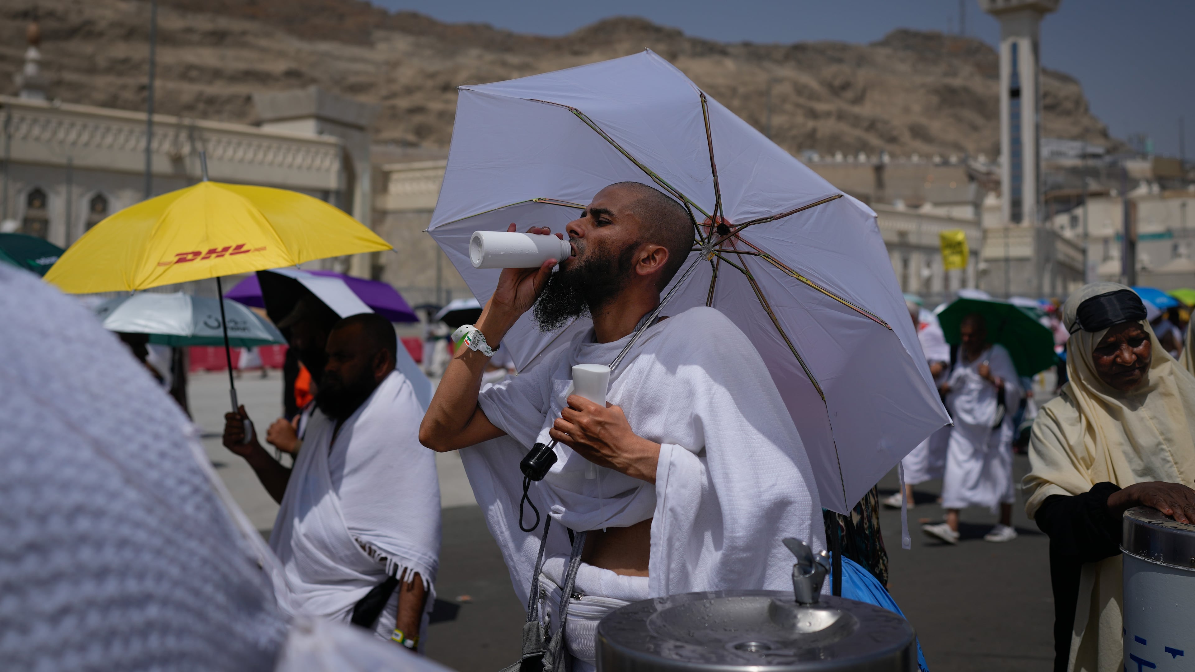 A Muslim pilgrim drinks water as pilgrims walk on their way to cast pebbles at pillars in the symbolic stoning of the devil, the last rite of the annual Hajj, in Mina near the holy city of Mecca, Saudi Arabia, Wednesday, May 27, 2026. (AP Photo/Altaf Qadri)