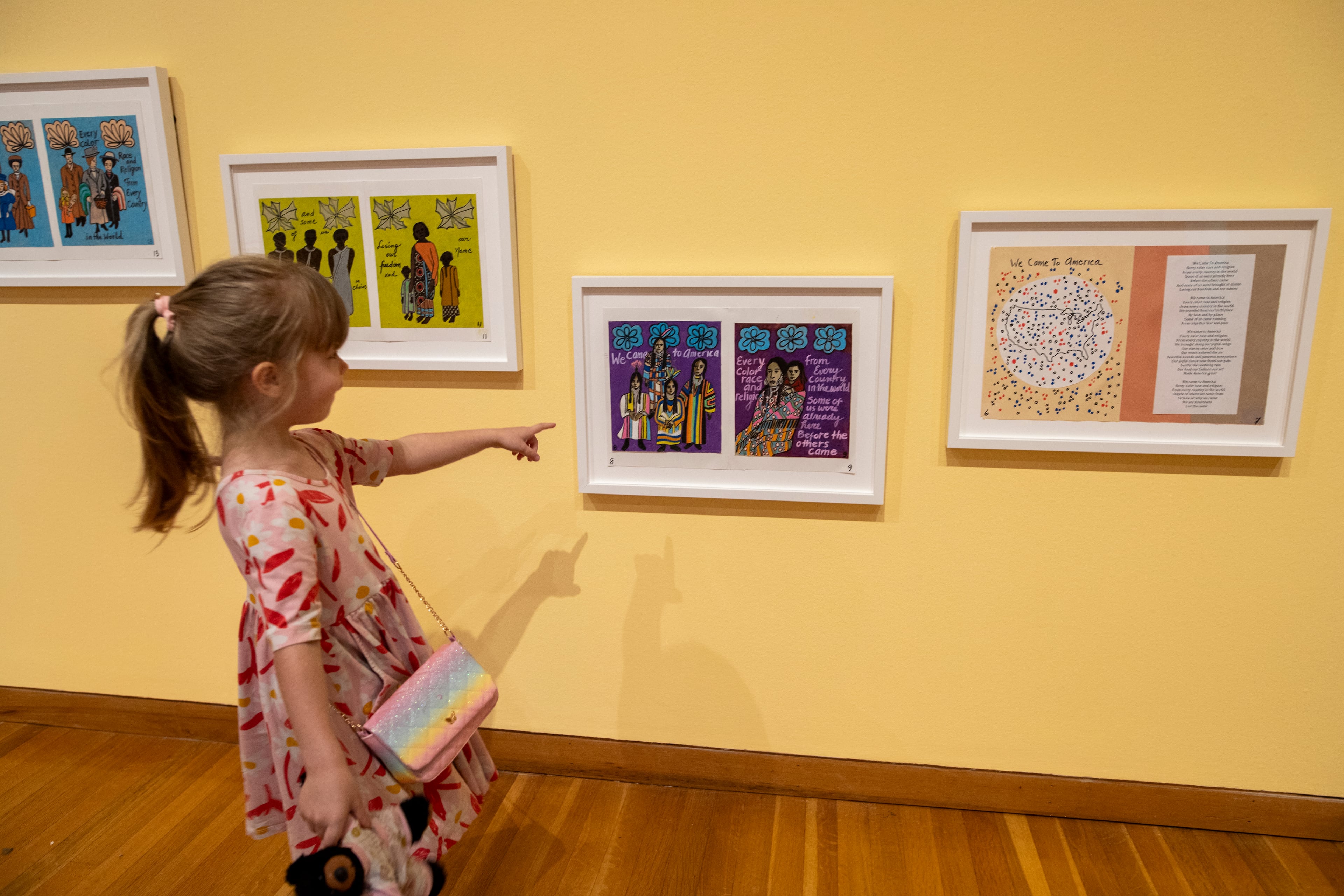 A young visitor to "Faith Ringgold: Seeing Children" sees something of interest among the framed book illustrations by the multimedia artist. The High Museum exhibit continues through Oct. 12. (Courtesy of Isadora Pennington)