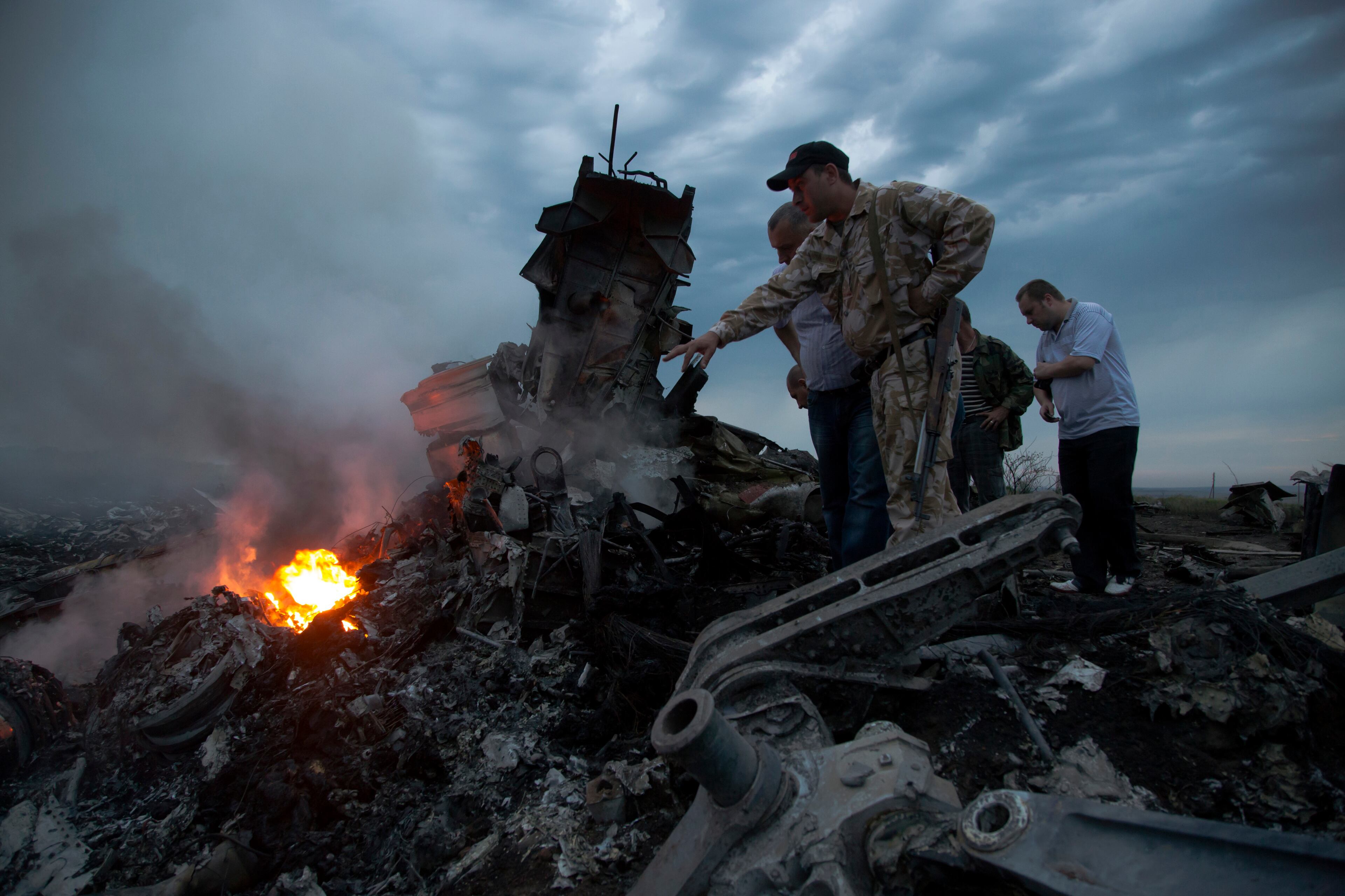 People inspect the crash site of a passenger plane near the village of Grabovo, Ukraine, Thursday, July 17, 2014. Ukraine said a passenger plane carrying 295 people was shot down Thursday as it flew over the country, and both the government and the pro-Russia separatists fighting in the region denied any responsibility for downing the plane. (AP Photo/Dmitry Lovetsky)
