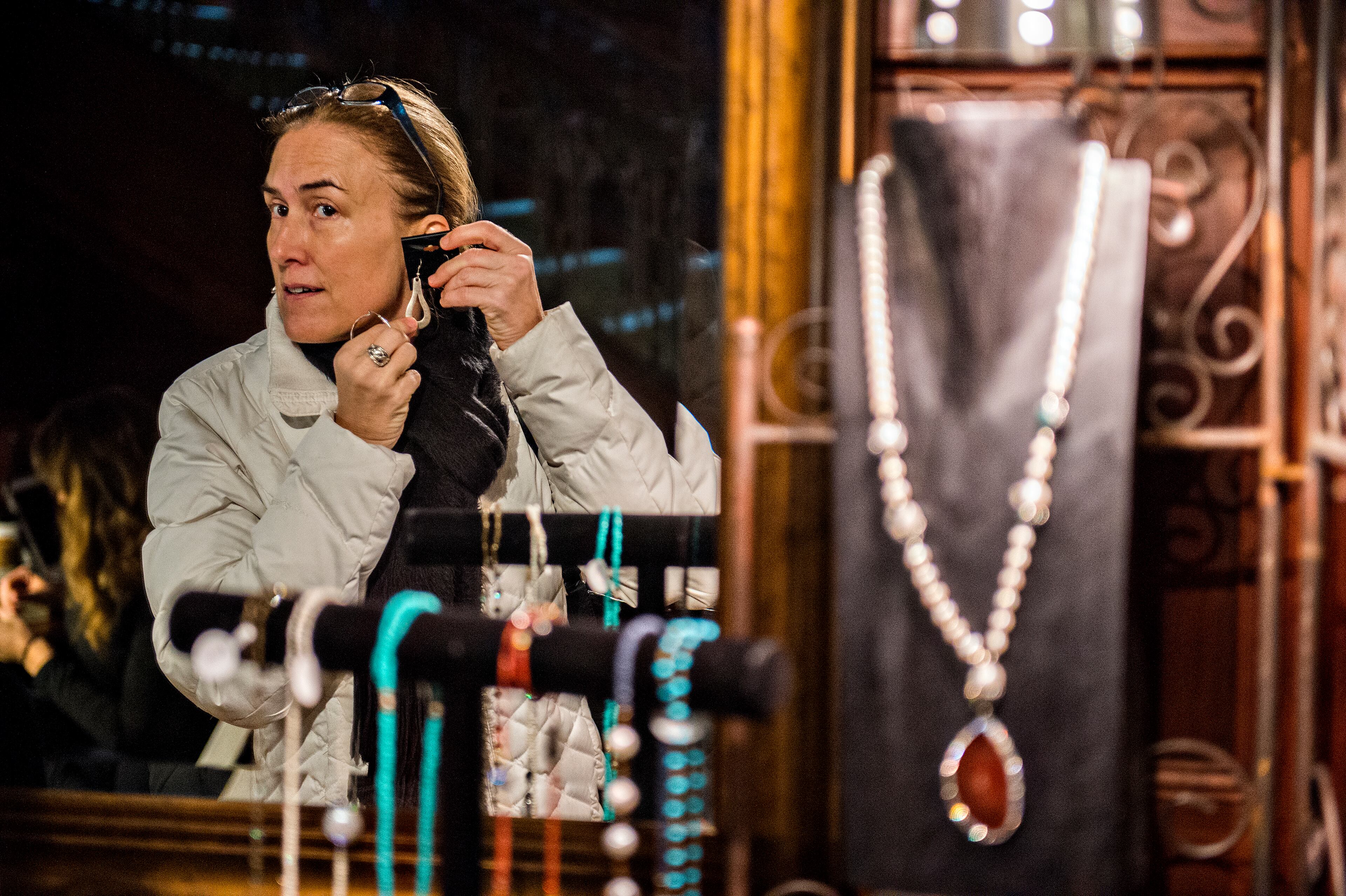 Michelle Hollberg (left) holds a pair of earrings designed by Martha Serezli to her ear during the Callanwolde Arts Festival in Atlanta on Saturday, January 23, 2016. JONATHAN PHILLIPS / SPECIAL