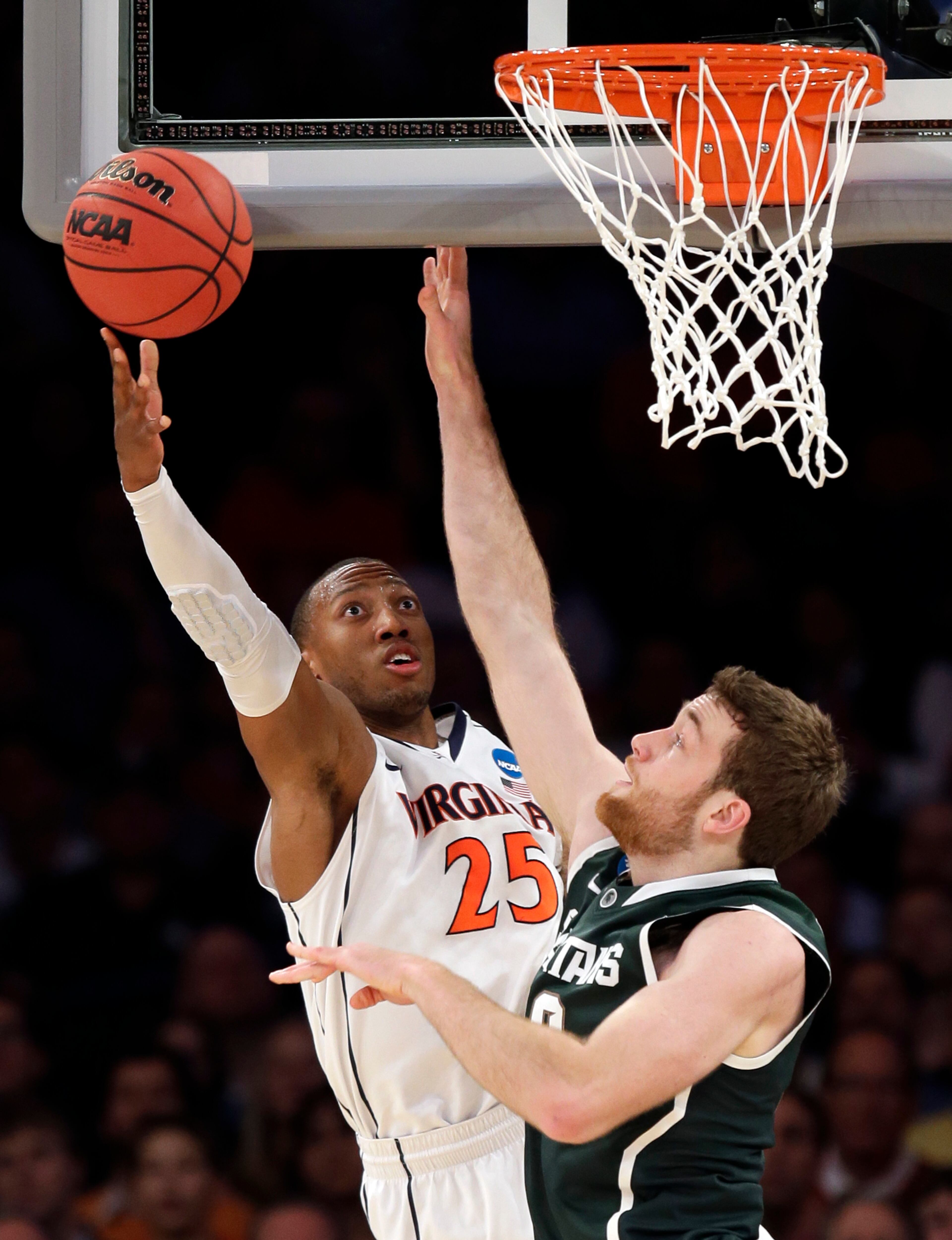 Virginia forward Akil Mitchell, left, goes up for a shot against Michigan State forward Matt Costello during the first half in a regional semifinal of the NCAA men's college basketball tournament, Friday, March 28, 2014, in New York.