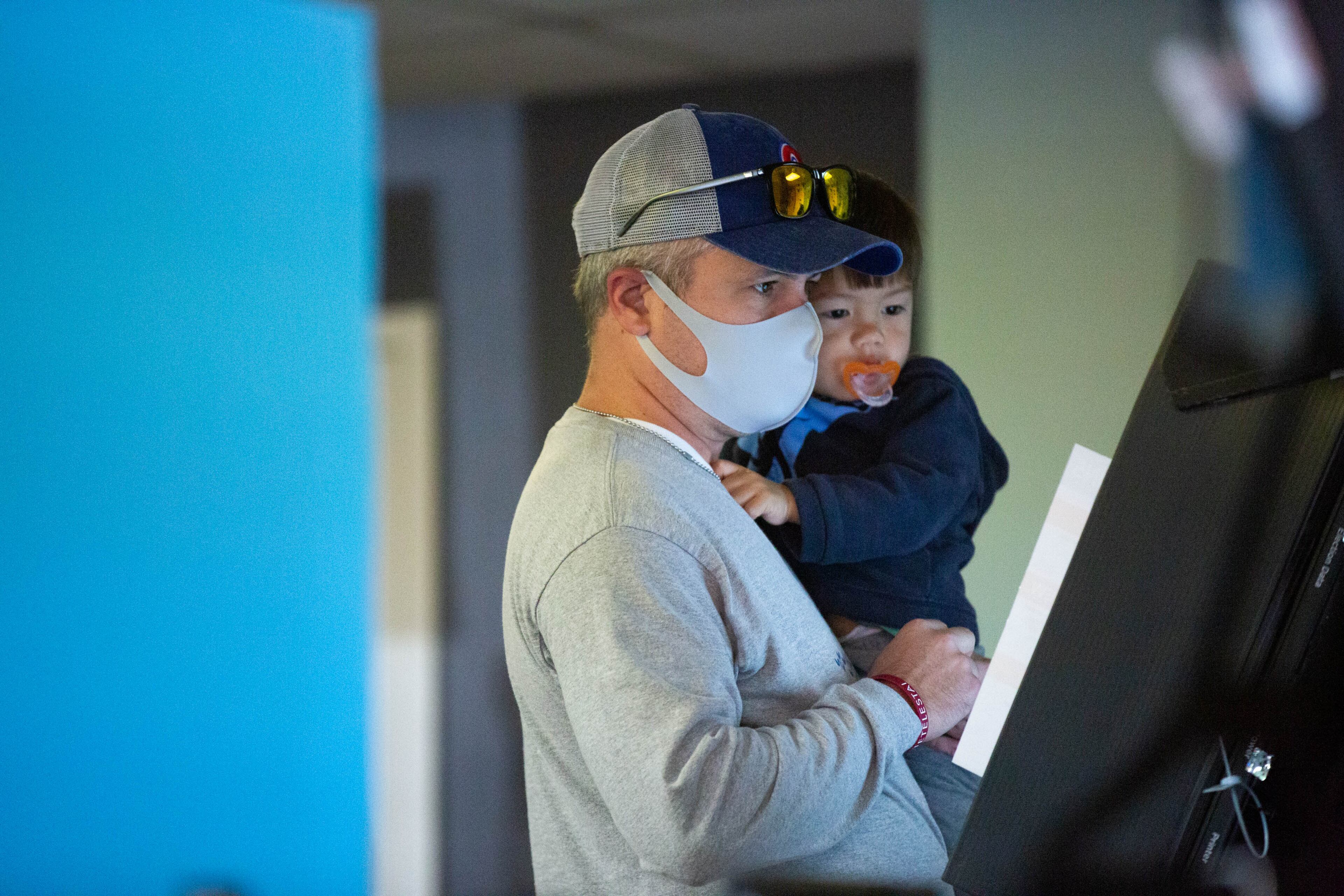 Cole Granthan holds his son Evan while voting at Life Church Smyrna Assembly of God in Smyrna, Georgia, on Tuesday, Nov. 3, 2020. (Rebecca Wright for the Atlanta Journal-Constitution)