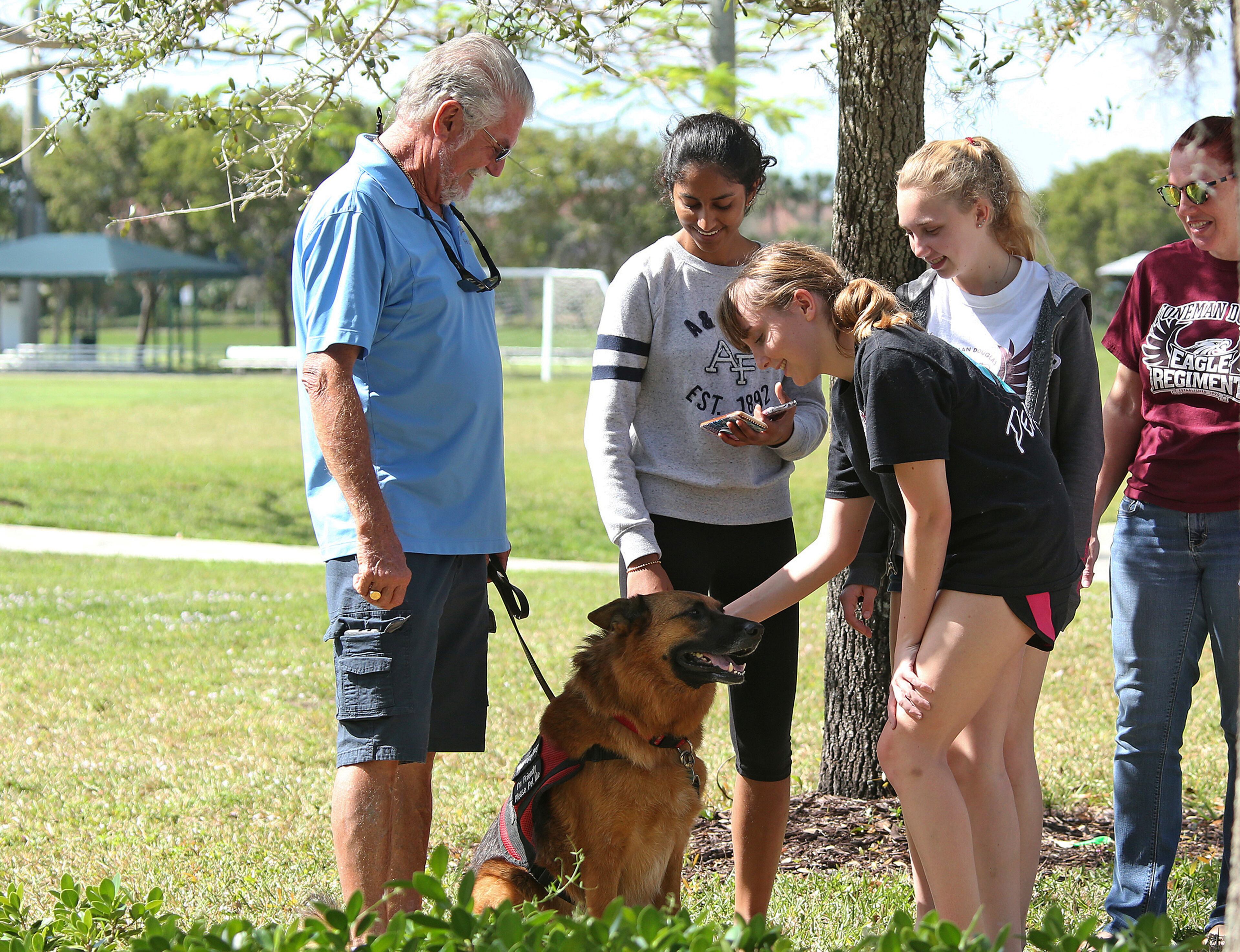 Grieving students pet Coco, a therapy dog outside Pines Trail Center where grief counselors are present, Thursday, Feb. 15, 2018 in Parkland, Fla. Nikolas Cruz was charged with 17 counts of premeditated murder Thursday morning. (AP Photo/Joel Auerbach)