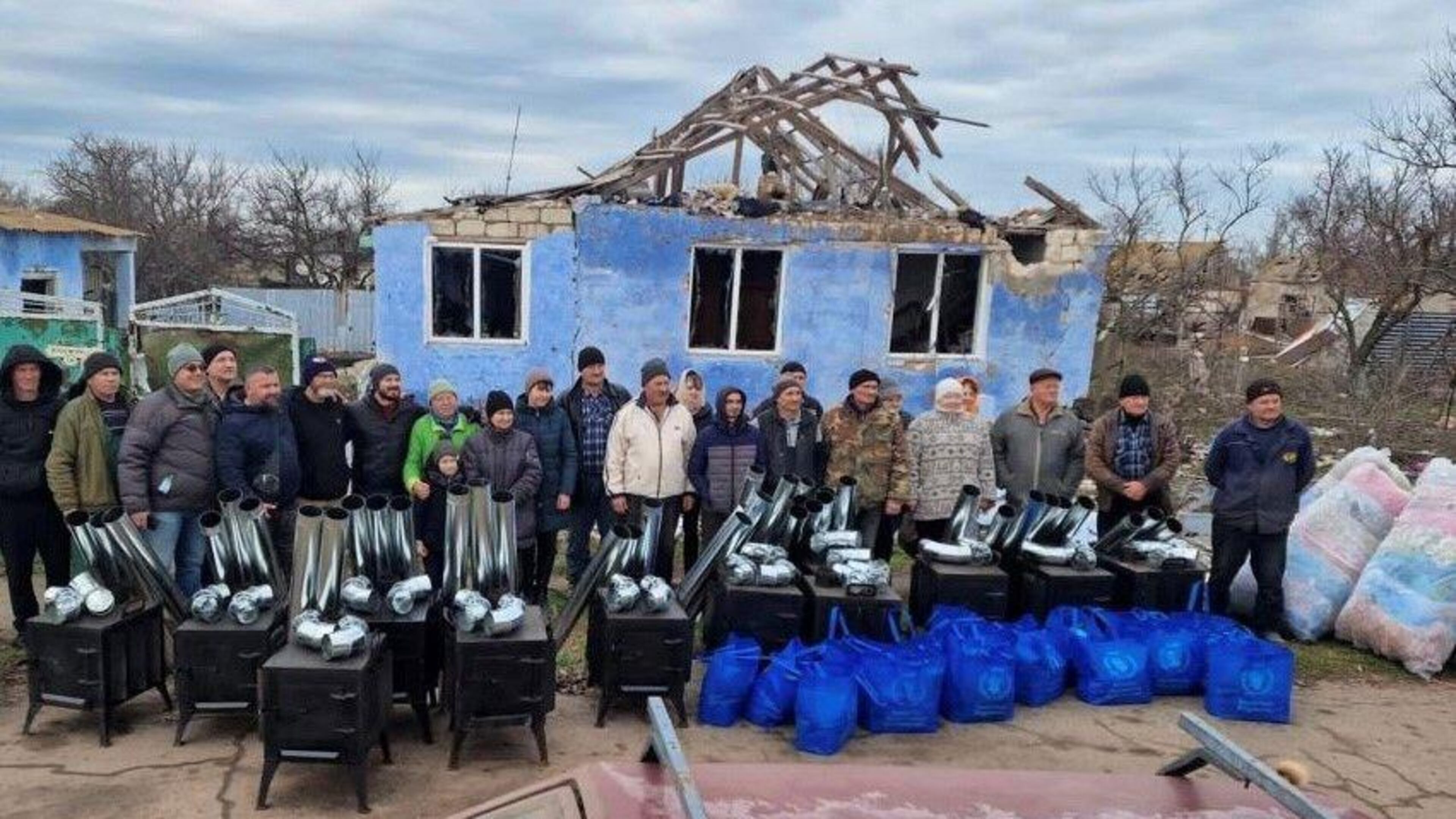 Ken Ward and volunteers stand in front of a damaged home in Ukraine, before handing out blankets and installing wood-fired stoves, which can be used for both heating and cooking. (Photo Courtesy of HelpingUkraine.U.S.)