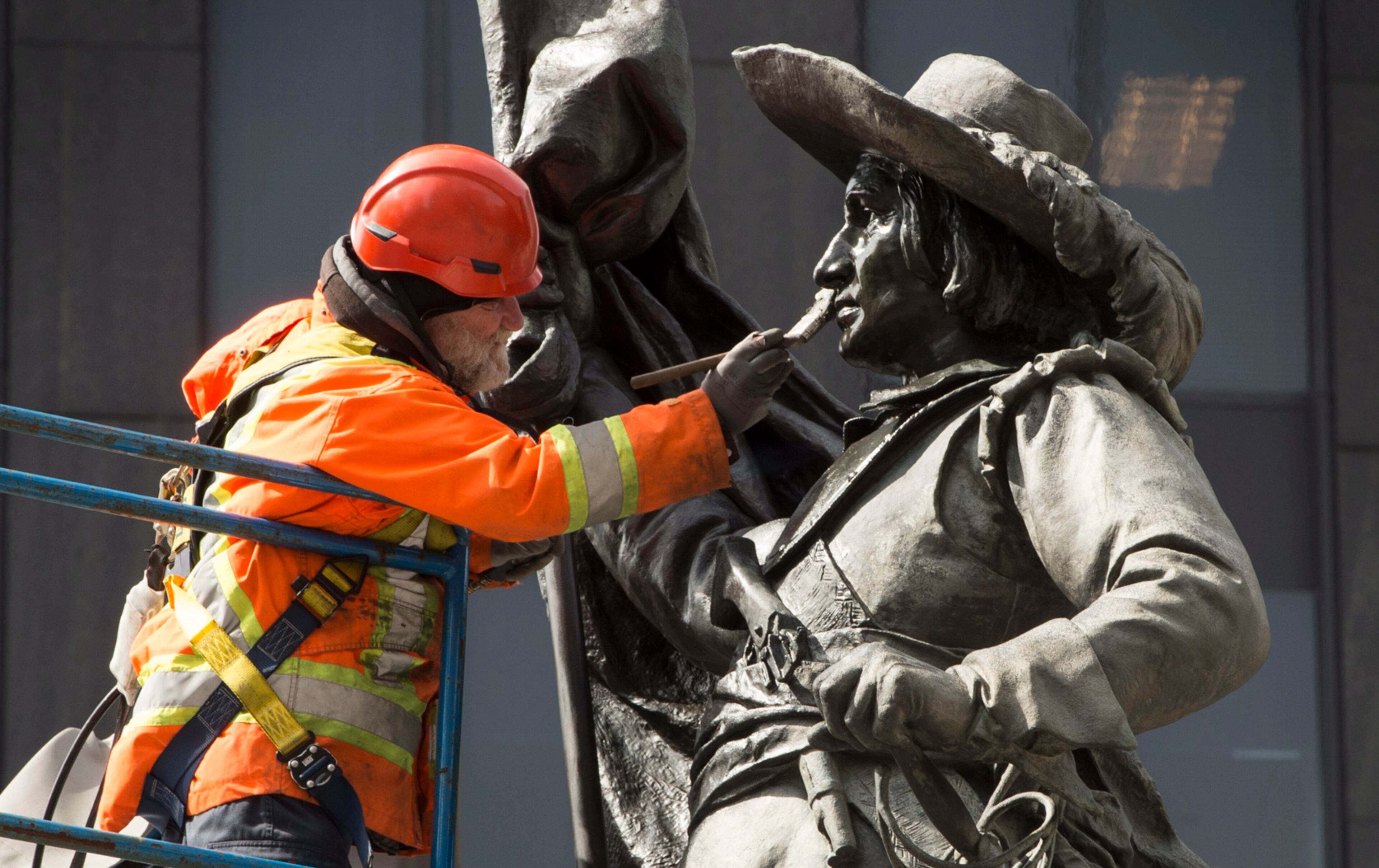 A worker cleans the stature of Paul de Chomedy de Maisonneuve, the founder of Montreal, Tuesday, April 25, 2017 in Montreal. The city of Montreal is celebrating its 375th anniversary this year. (Paul Chiasson/The Canadian Press via AP)