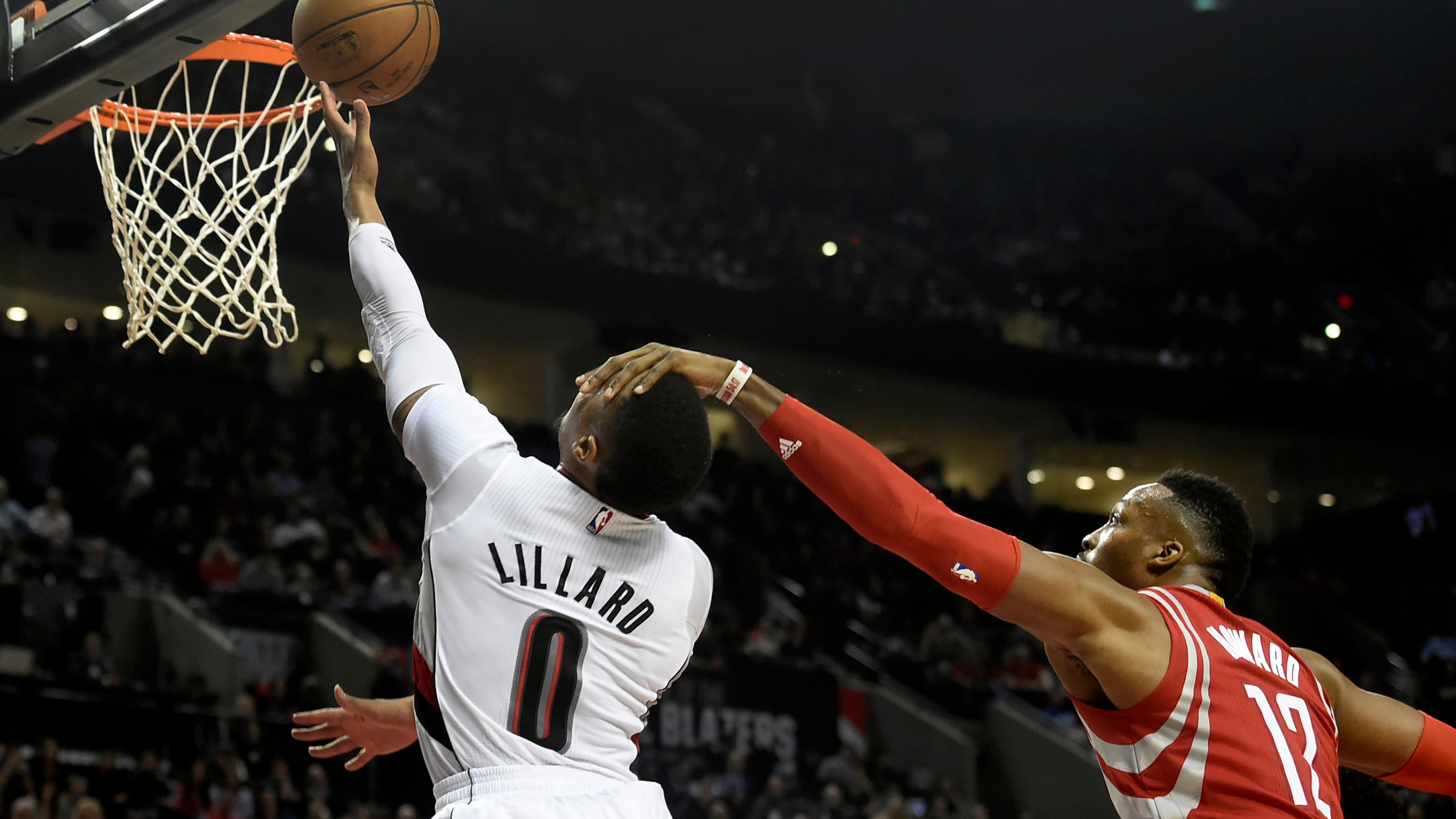 Portland Trail Blazers guard Damian Lillard (0) is fouled by Houston Rockets center Dwight Howard (12) as he drives to the basket during the second half of an NBA basketball game in Portland, Ore., Wednesday, Feb. 10, 2016. The Blazers won the game 116-103. (AP Photo/Steve Dykes)