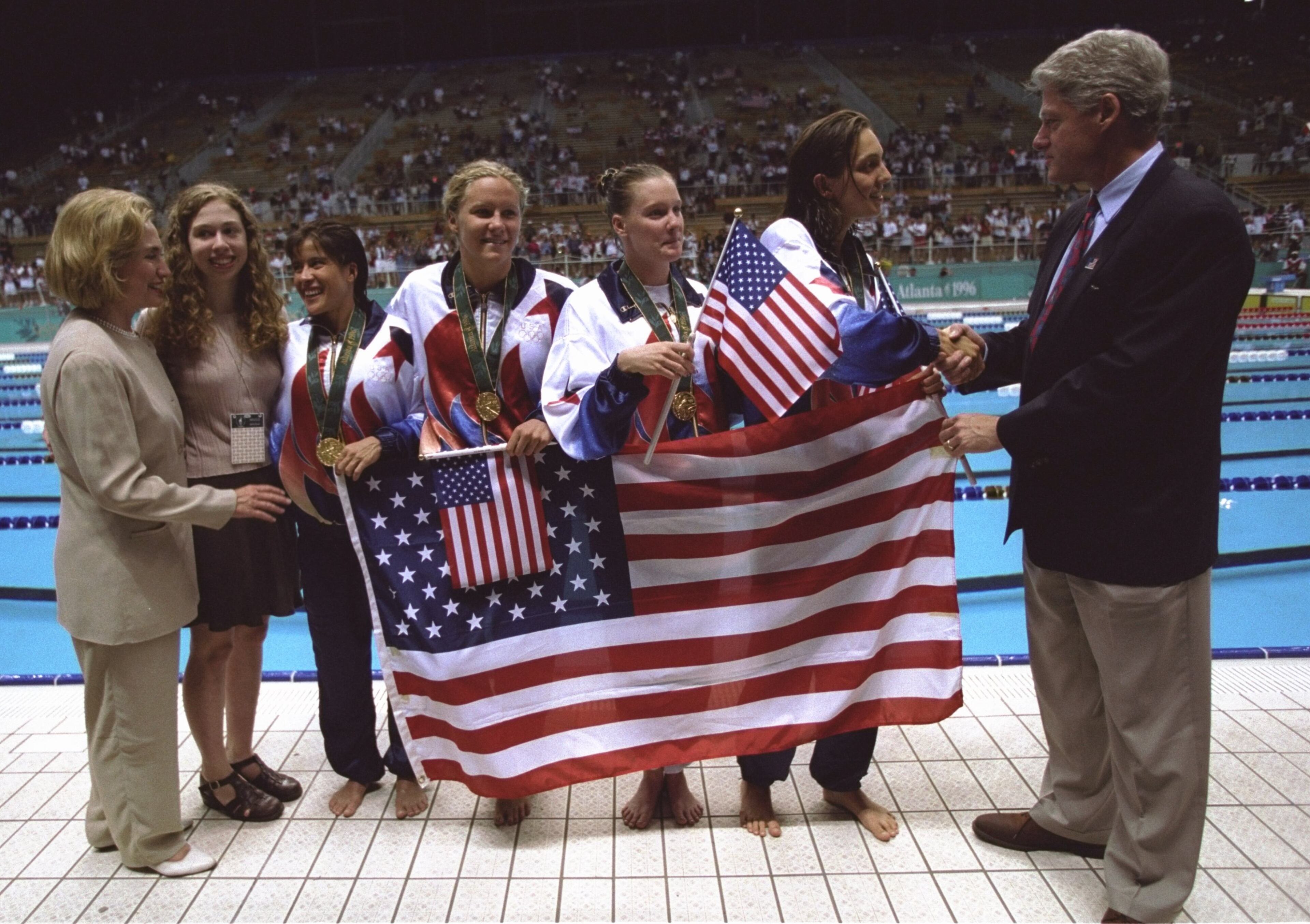From left to right: Hillary Clinton, Chelsea Clinton, Sheila Taormina, Jenny Thompson, Trina Jackson, Christina Teuscher President Bill Clinton pose together with the American flag after the USA wins the gold medal in the women's 4x200m freestyle relay at the Georgia Tech Aquatic Center at the 1996 Centennial Olympic Games in Atlanta, Georgia. \ Mandatory Credit: Simon Bruty /Allsport