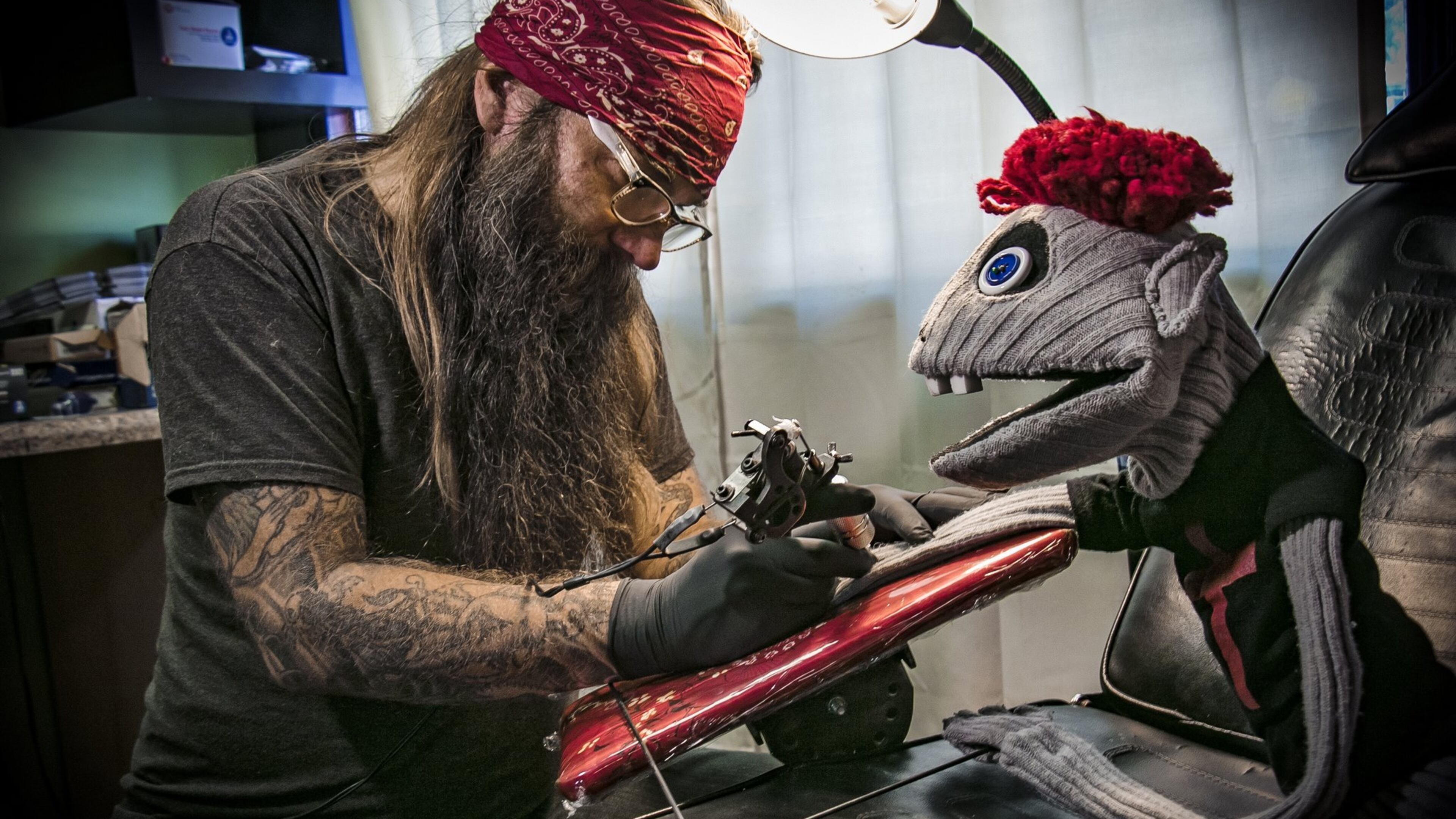 Tyrone, a bad puppet from the Alliance Theatre production “Hand to God,” decides it’s time to get a tattoo on his cloth arm from artist Jett Bryant. CONTRIBUTED