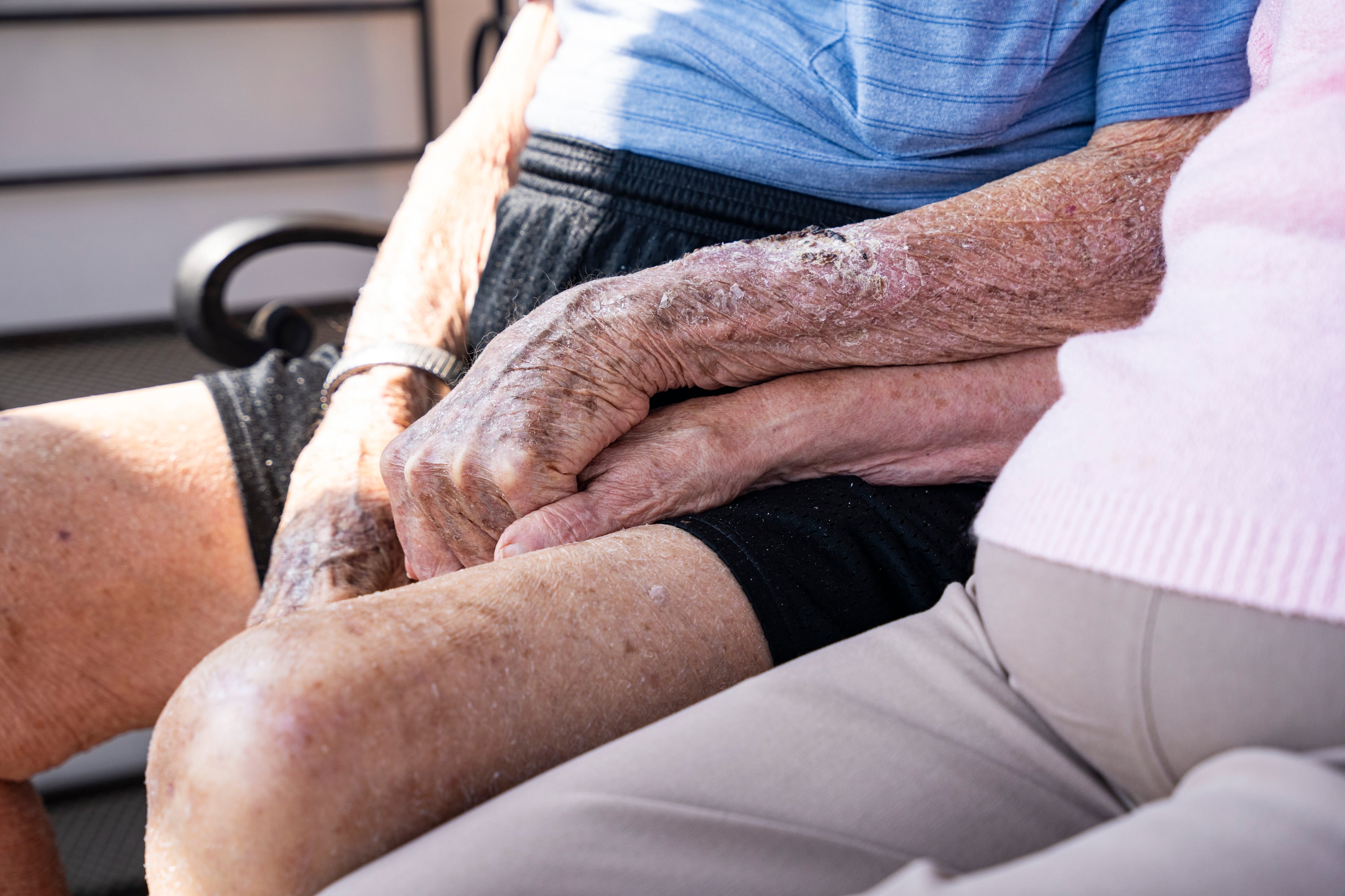 Frank Stovall, who is 103, holds hands with Agnes Benson, 91, as they sit on the balcony of his Sandy Springs condo. They often watch sunrises together. Americans living to at least 100 years are growing in number and as a proportion of the nation. (Olivia Bowdoin for the AJC).