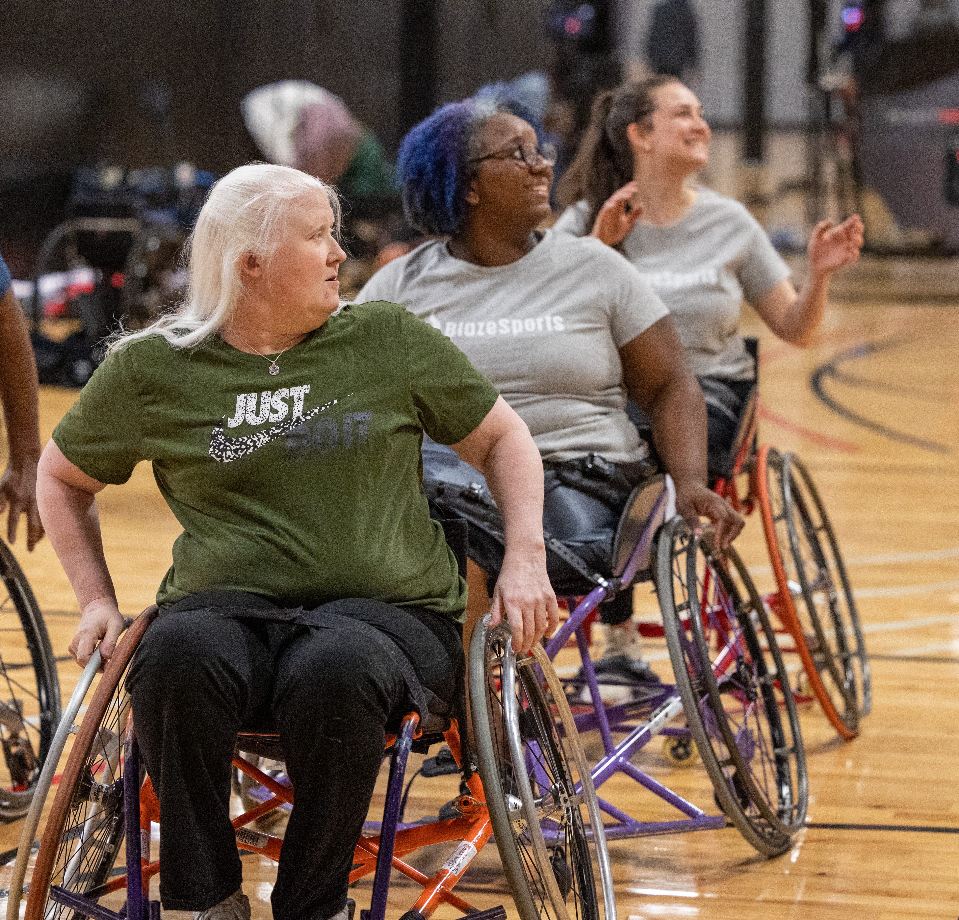 The Lady Ballers wheelchair team members Carrie Willoughby (from left), Patria Brown and Lexi Sklar listen to instructions during practice at Shoot 360 in Alpharetta. PHIL SKINNER FOR THE ATLANTA JOURNAL-CONSTITUTION