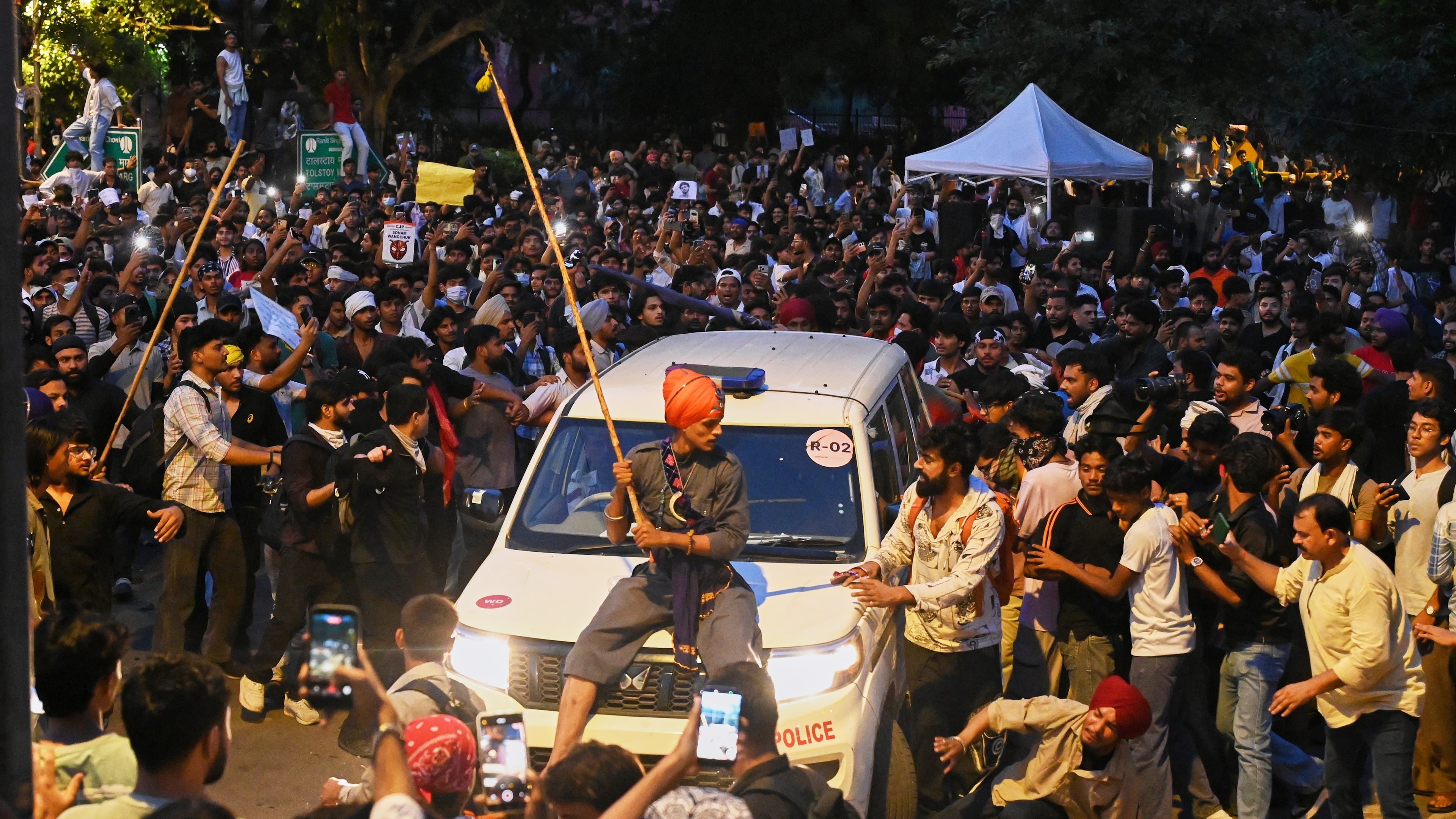 A protestor sits on the hood of a police car during a demonstration demanding educational reforms as part of the Cockroach Janta Party's ongoing protest movement in New Delhi, India, Wednesday, July 22, 2026. (AP Photo/Vipin)