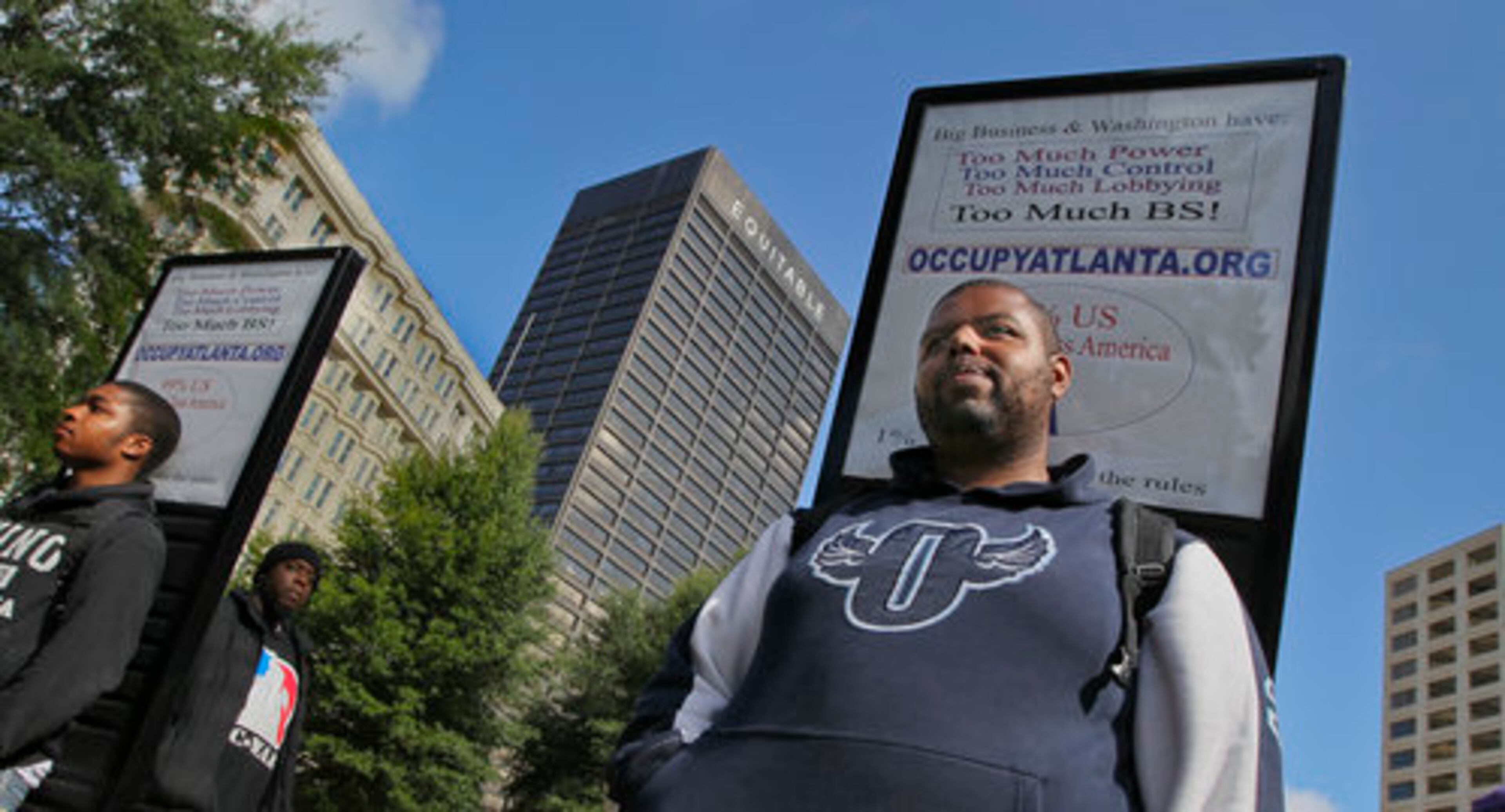 Darius Hardy (left) and Morehouse graduate Jason Woody (right) wear placards on their backs spelling out Occupy Atlanta's concerns Thursday.