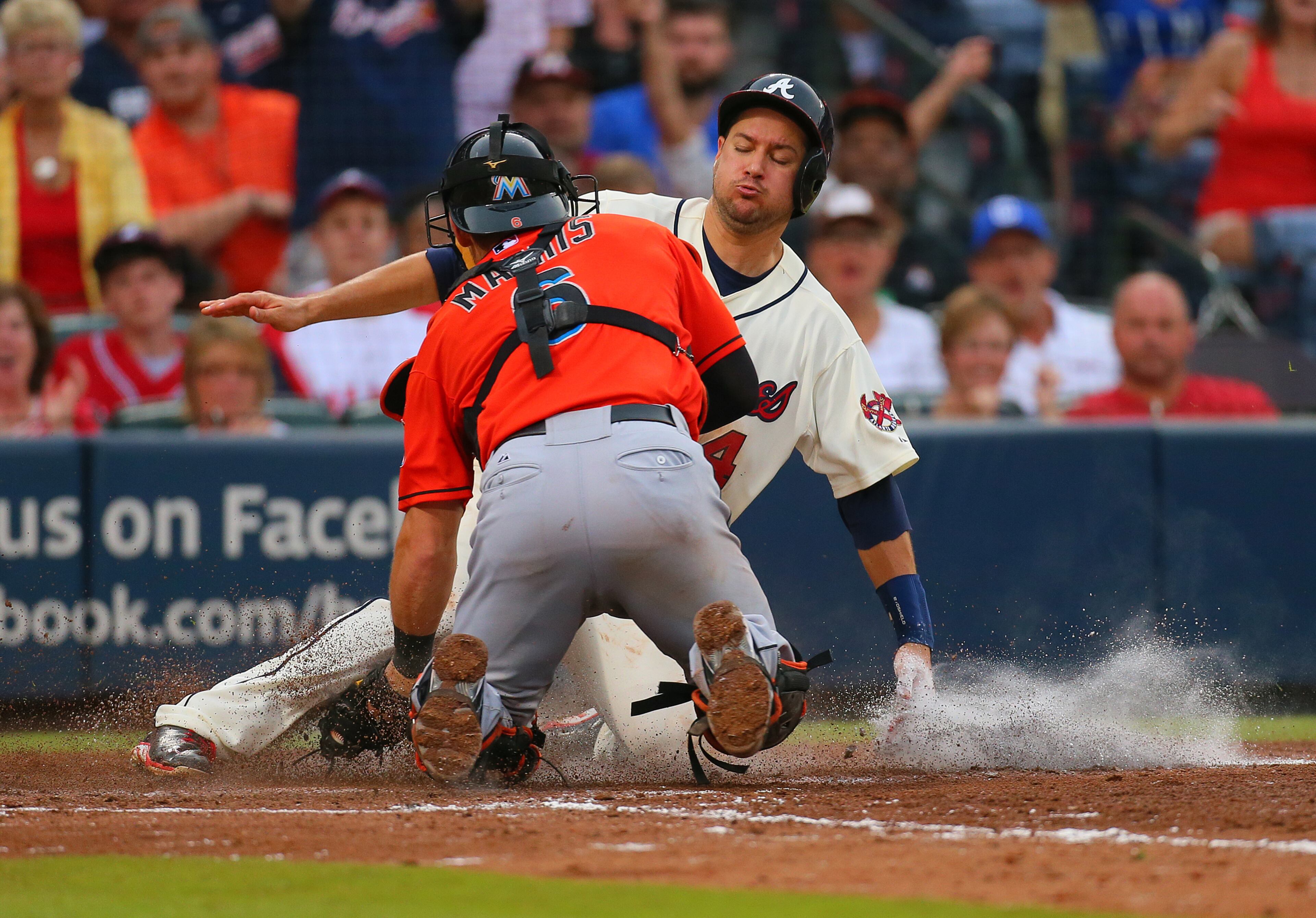 The Braves' Paul Janish is tagged out at home by Marlins catcher Jeff Mathis trying to score on a single by Jose Constanza during the 7th inning of their MLB baseball game on Sunday, Sept. 1, 2013, in Atlanta. The Braves lost 7-0.
