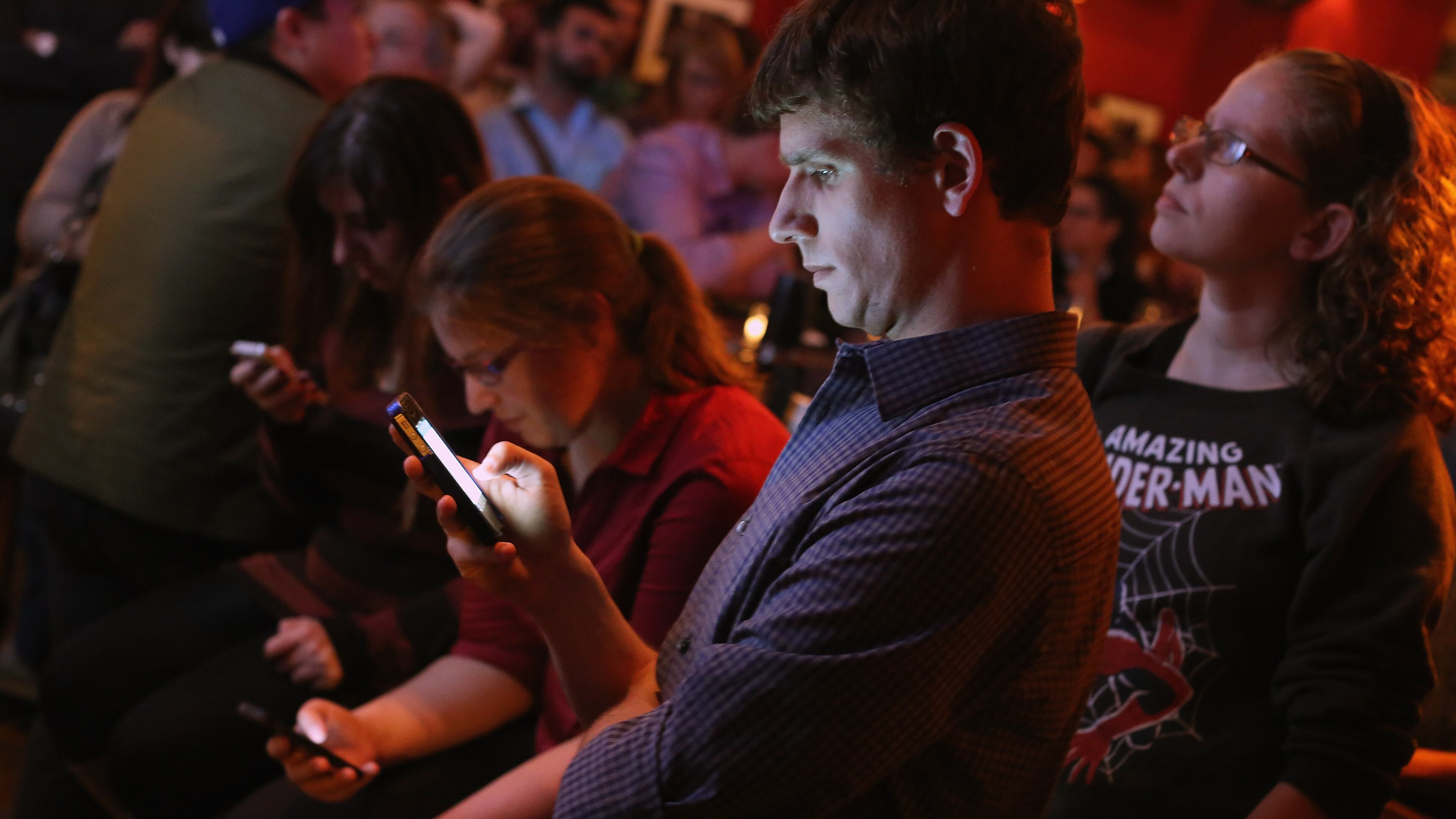 Young adults split their attention between a televisied debate and scanning Twitter on their smart phones. (Photo by Chip Somodevilla/Getty Images)