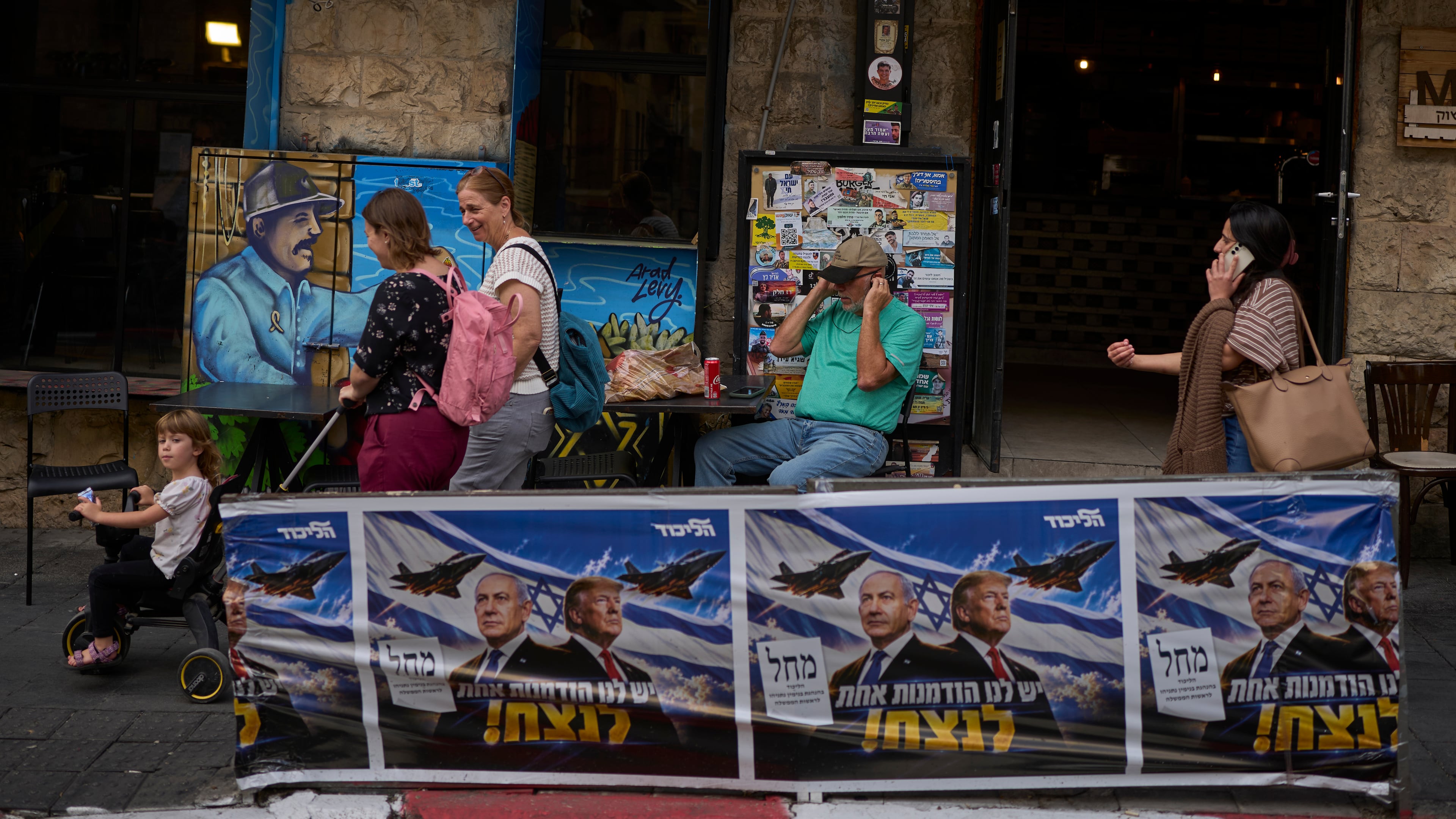 People walk next to a Likud party campaign ad featuring Israeli Prime Minister Benjamin Netanyahu and U.S. President Donald Trump, with a Hebrew message reading "We have one opportunity to win," in Jerusalem on Wednesday, Oct. 28, 2026, a day after the elections in Israel. (AP Photo/Ohad Zwigenberg)