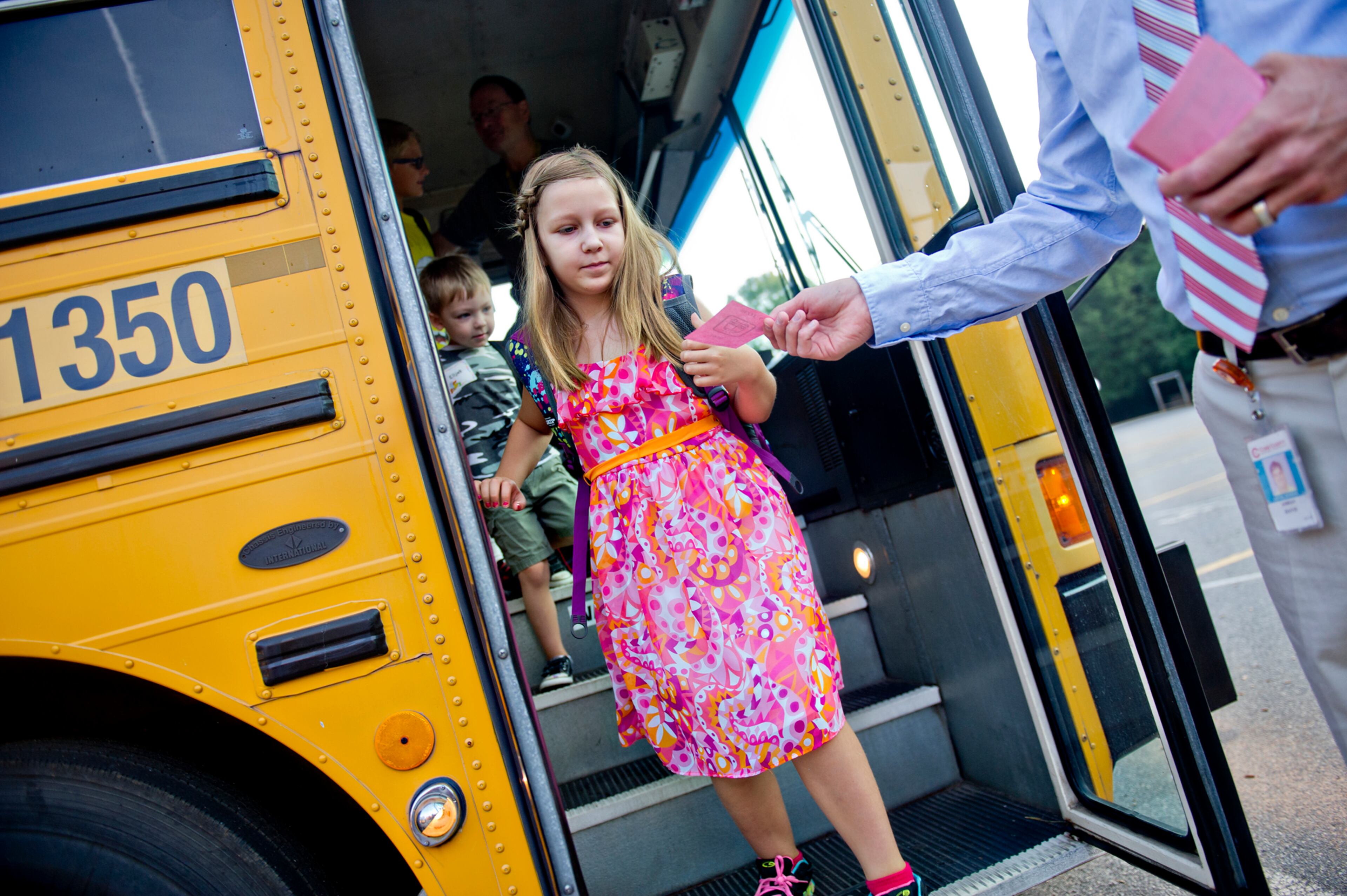 Selah Christopher (center) is handed a notecard as she steps off the bus with her brother Elijah at Davis Elementary School in Marietta on Monday, August 4, 2014. Teachers and administrators at the school dressed as pirates for the first day of classes. Students in Cobb County and Atlanta public schools headed back to class on Monday for the new school year. JONATHAN PHILLIPS / SPECIAL