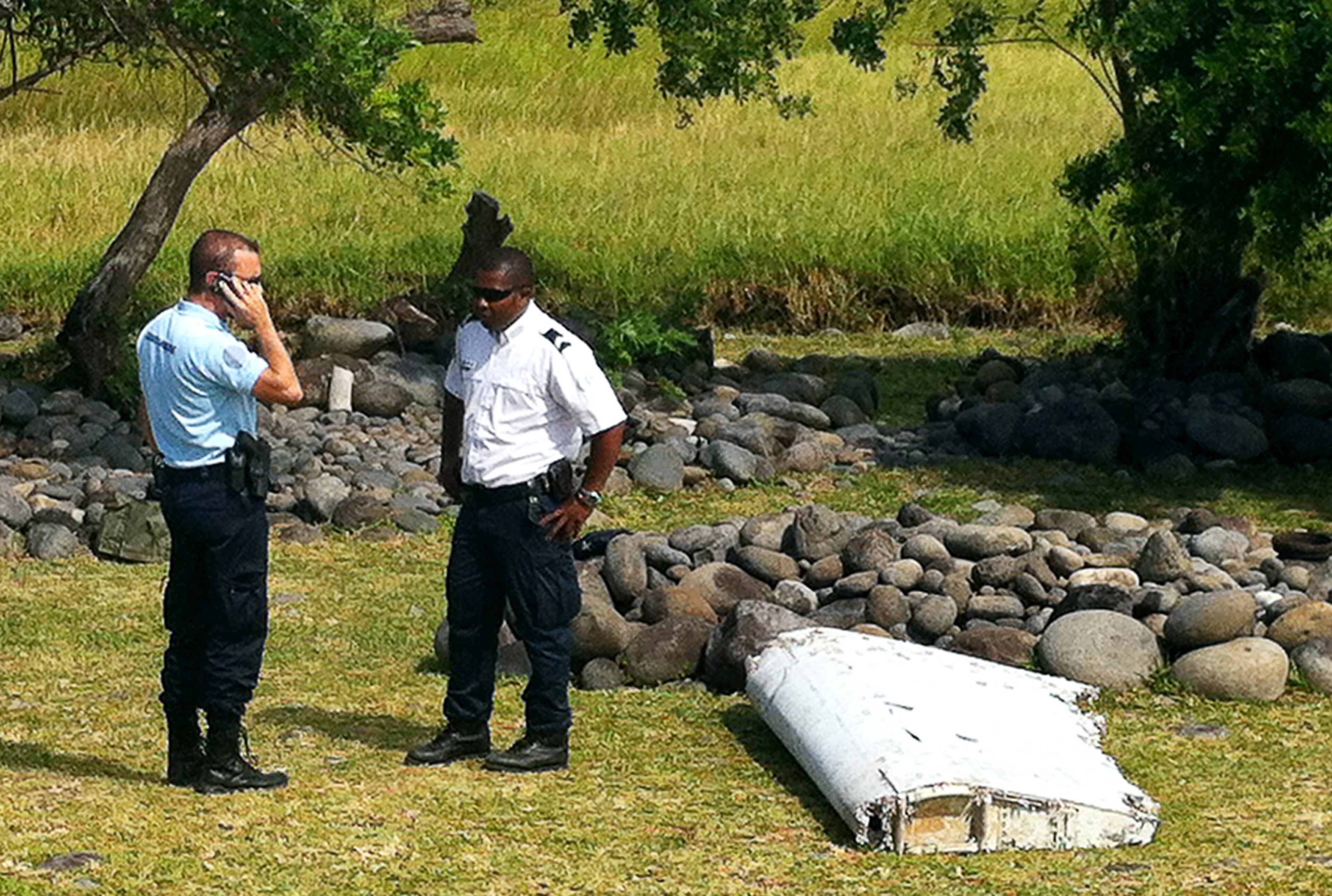 A policeman and a gendarme stand next to a piece of debris from an unidentified aircraft found in the coastal area of Saint-Andre de la Reunion, in the east of the French Indian Ocean island of La Reunion, on July 29, 2015. The two-metre-long debris, which appears to be a piece of a wing, was found by employees of an association cleaning the area and handed over to the air transport brigade of the French gendarmerie (BGTA), who have opened an investigation. An air safety expert did not exclude it could be a part of the Malaysia Airlines flight MH370, which went missing in the Indian Ocean on March 8, 2014. (Photo: YANNICK PITOU/AFP/Getty Images)