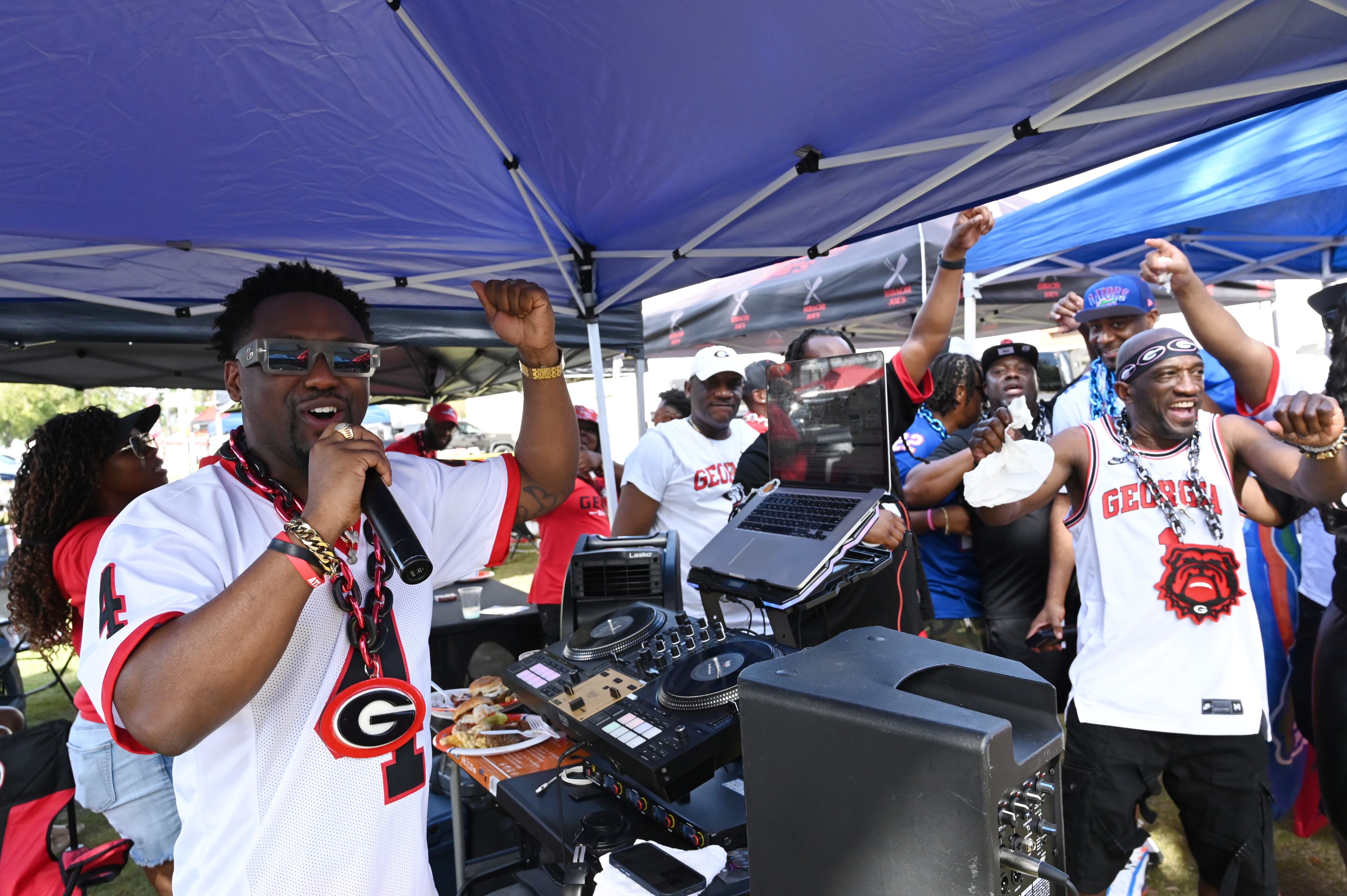 Georgia fans cheer as Tony Swinson, a.k.a DJ SWIN, (left) plays tunes outside EverBank Stadium ahead of the NCAA football game between Georgia and Florida, Saturday, November 2, 2024, in Jacksonville, Fla. (Hyosub Shin / AJC)