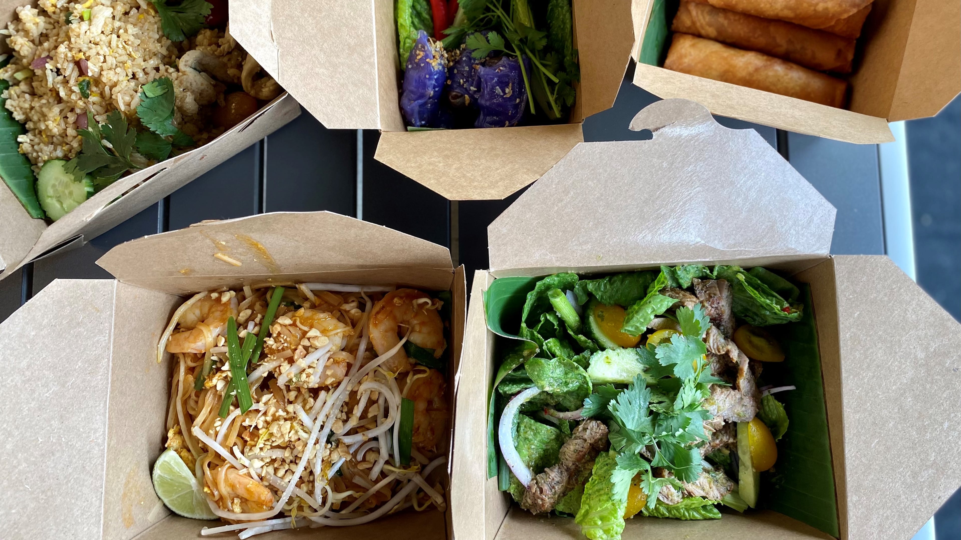 TydeTate Kitchen packs all its Thai comfort food in takeout boxes. Clockwise from upper left: chicken fried rice, saku bites, spring rolls, Thai beef salad and pad Thai. Wendell Brock for The Atlanta Journal-Constitution