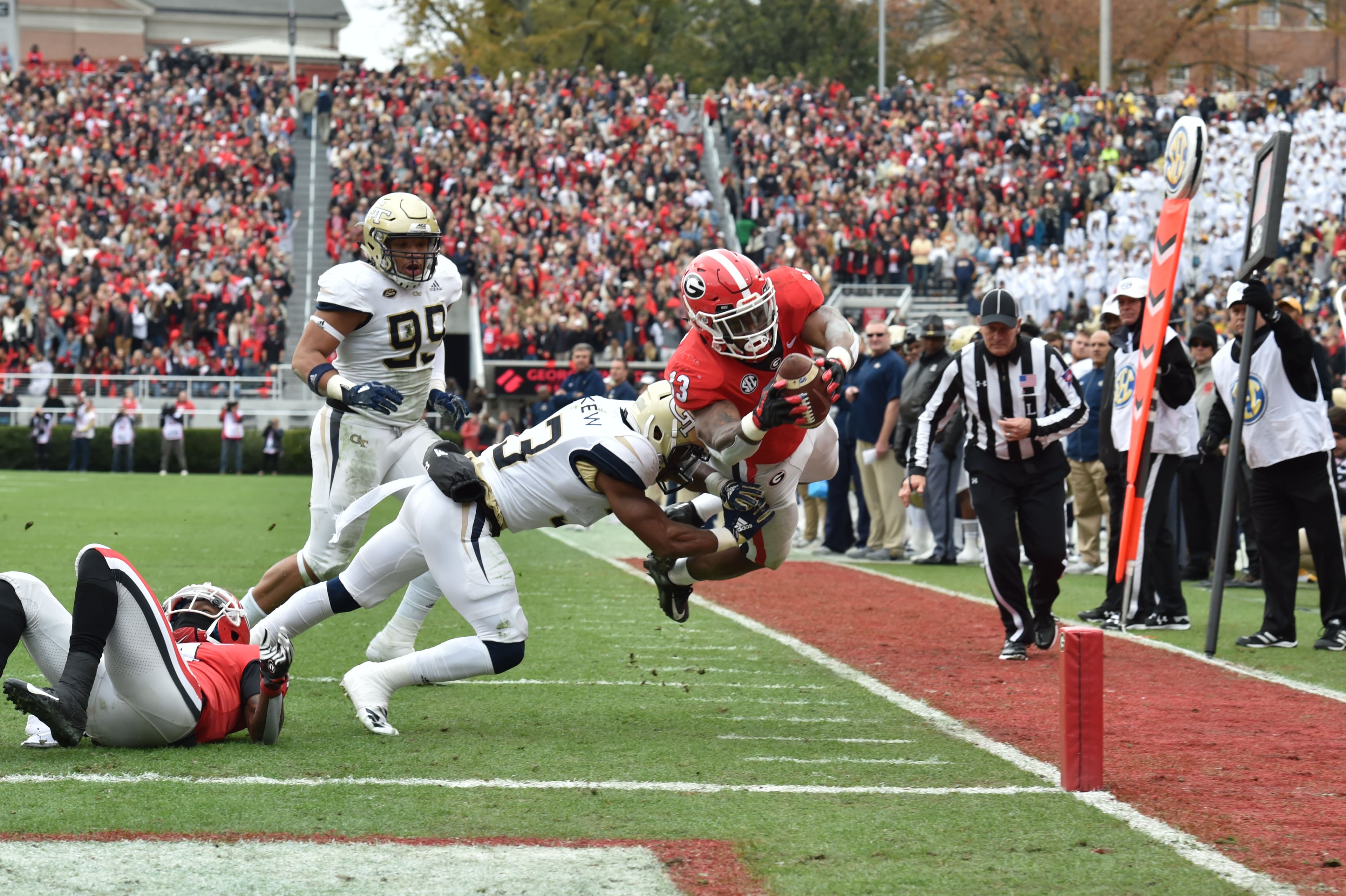 November 24, 2018 Athens - Georgia running back Elijah Holyfield (13) falls into the endzone past Georgia Tech defensive back Jaytlin Askew (33) for a touchdown during the first half in a NCAA college football game at Sanford Stadium on Saturday, November 24, 2018. HYOSUB SHIN / HSHIN@AJC.COM