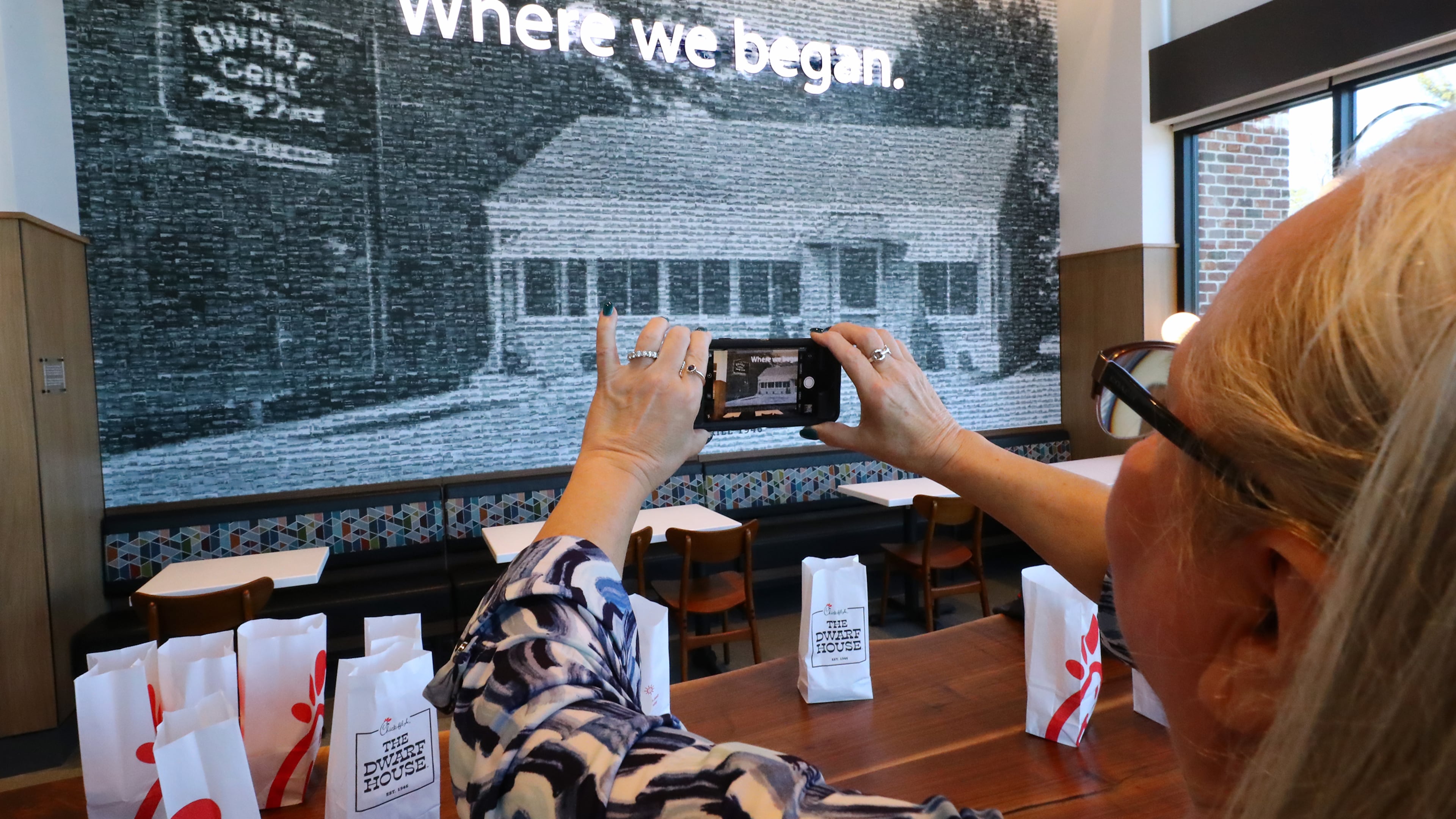 Teena Hammonds snaps a photo of a pixelated image of the original building comprised of photographs of 2,568 Chick-fil-A locations, on one of the walls inside the newly renovated Dwarf House, the first of Truett Cathey’s restaurants, on Monday, Feb. 14, 2022, in Hapeville.
“Curtis Compton / Curtis.Compton@ajc.com”`