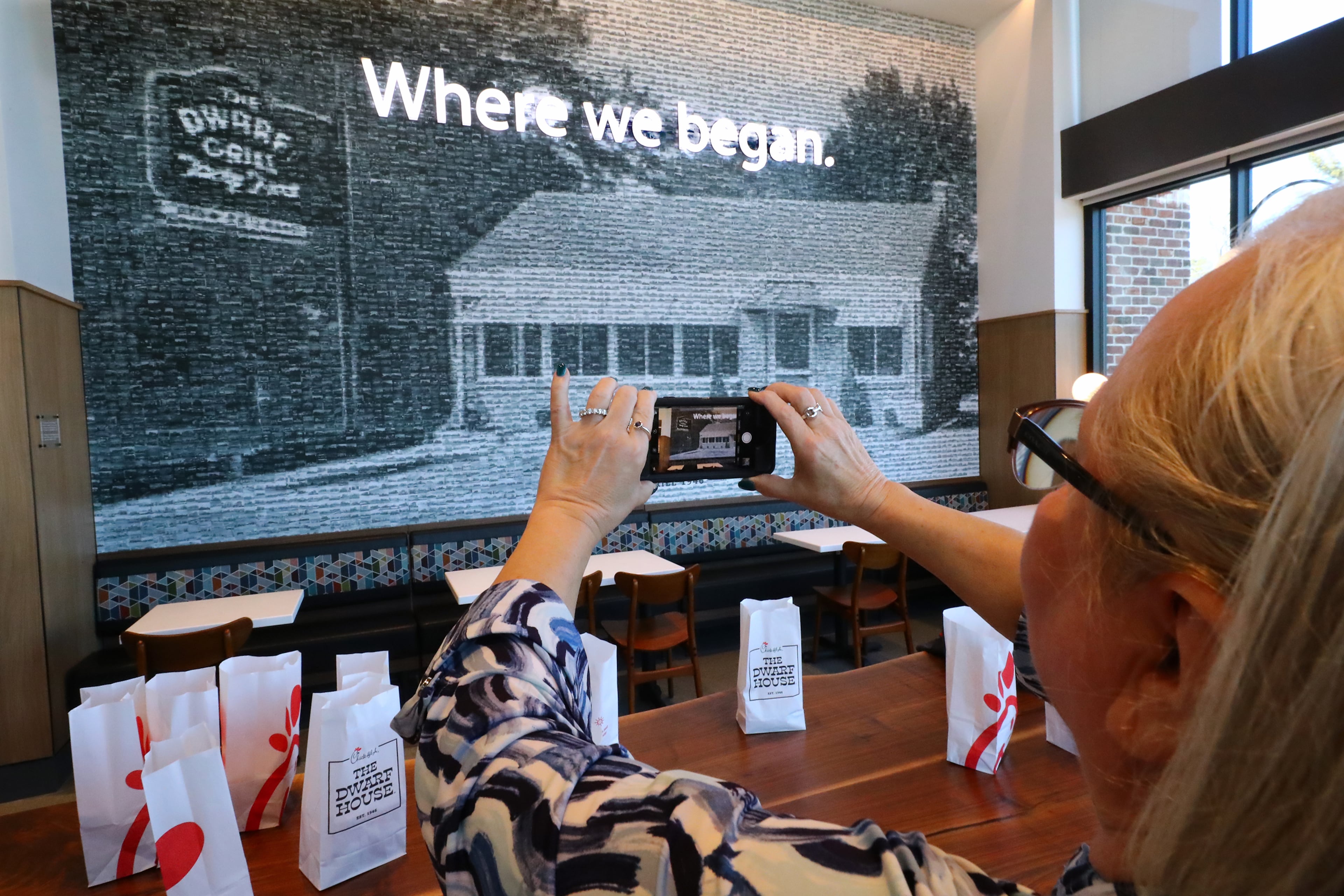 021422 Hapeville: Teena Hammonds snaps a photo of a pixelated image of the original building comprised of photographs of 2,568 Chick-fil-A locations, on one of the walls inside the newly renovated Dwarf House, the first of Truett Cathey’s restaurants, on Monday, Feb. 14, 2022, in Hapeville.
“Curtis Compton / Curtis.Compton@ajc.com”`