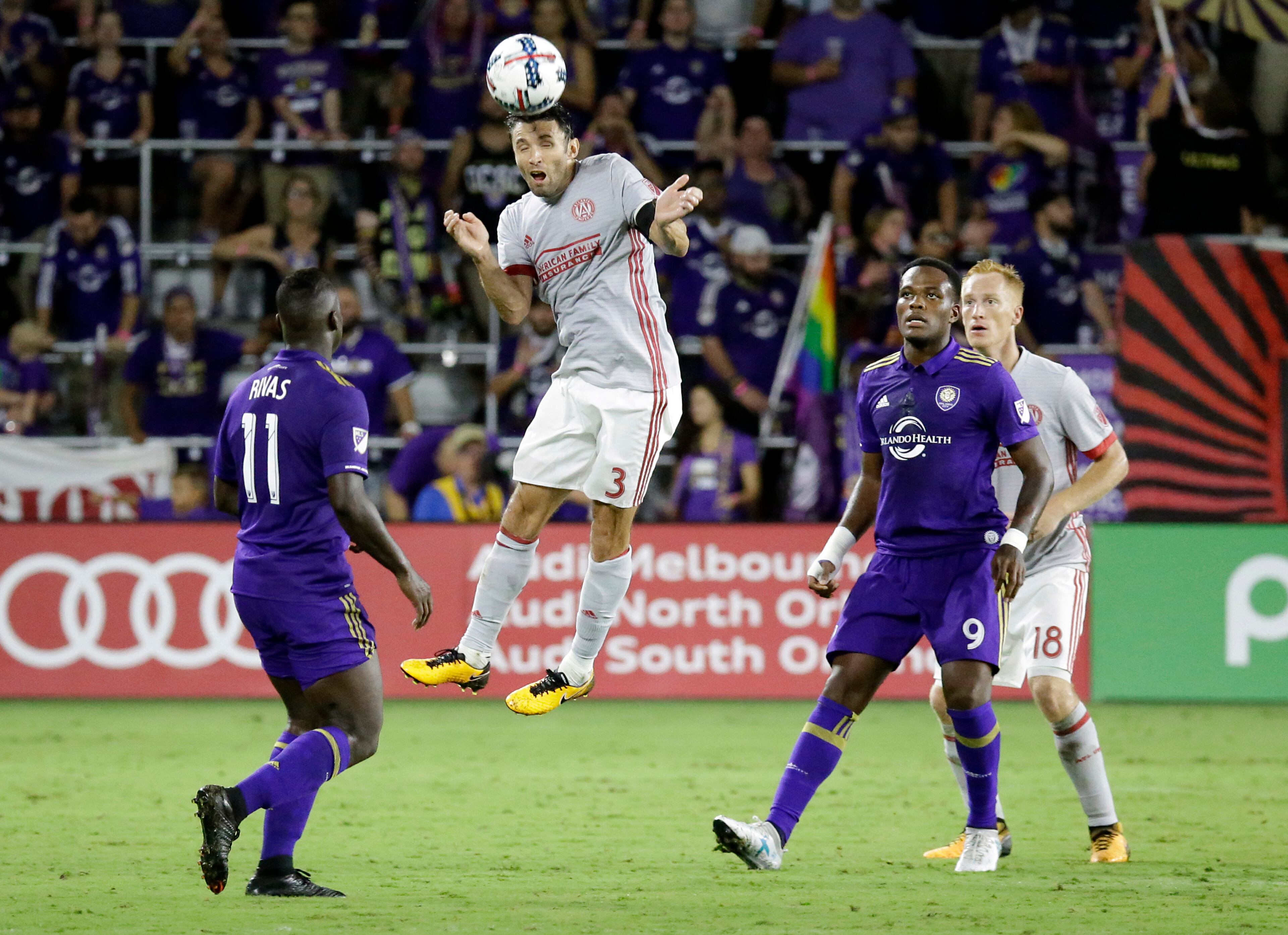 Atlanta United's Michael Parkhurst (3) heads the ball as he gets between Orlando City's Carlos Rivas (11) and Cyle Larin (9) during the second half of an MLS soccer match, Friday, July 21, 2017, in Orlando, Fla. Atlanta United won 1-0. (AP Photo/John Raoux)