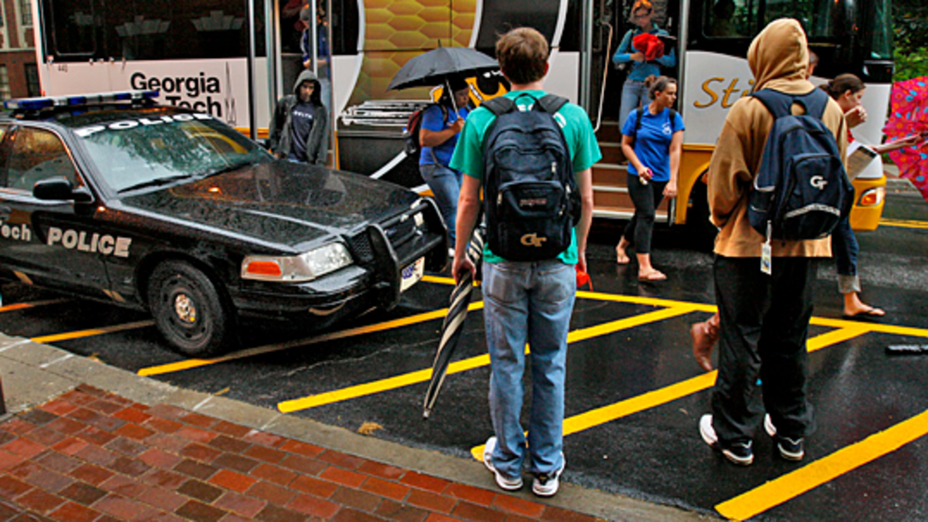 Students wait to board a Georgia Tech Stinger campus bus near police presence at Ferst Drive and Cherry Street. Students pay $85 a semester for transportation fees. The school has the highest amount of student fees of any public college or university in Georgia, at nearly $1,300 a semester. AJC FILE PHOTO.