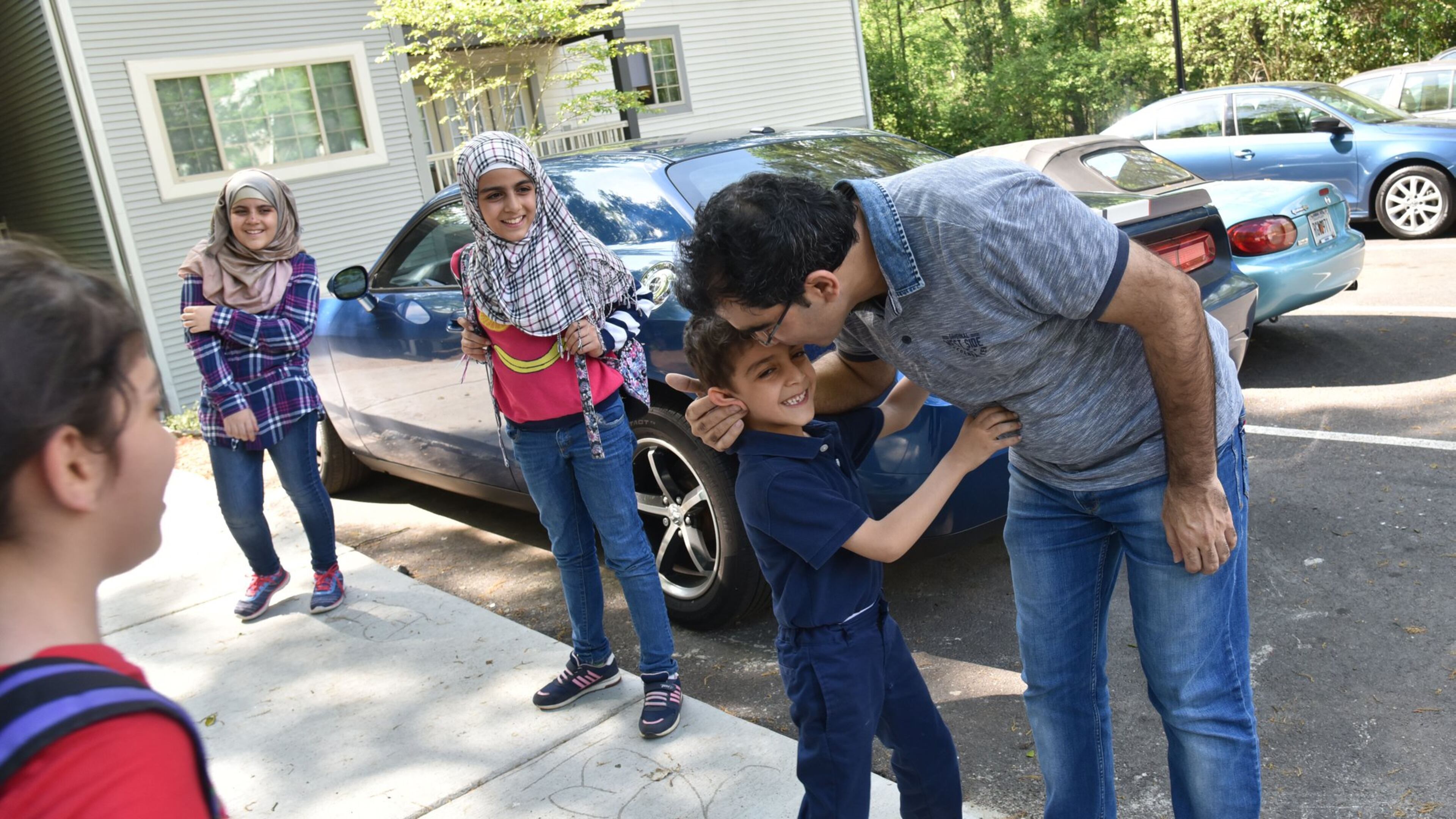 Yaser Musa kisses his son, Issa, 5, outside their Clarkston apartment as he waits for his other children (from left) Samar, 10, Nor Alhoda, 12, and Reem, 11, on April 13, 2017. HYOSUB SHIN / HSHIN@AJC.COM