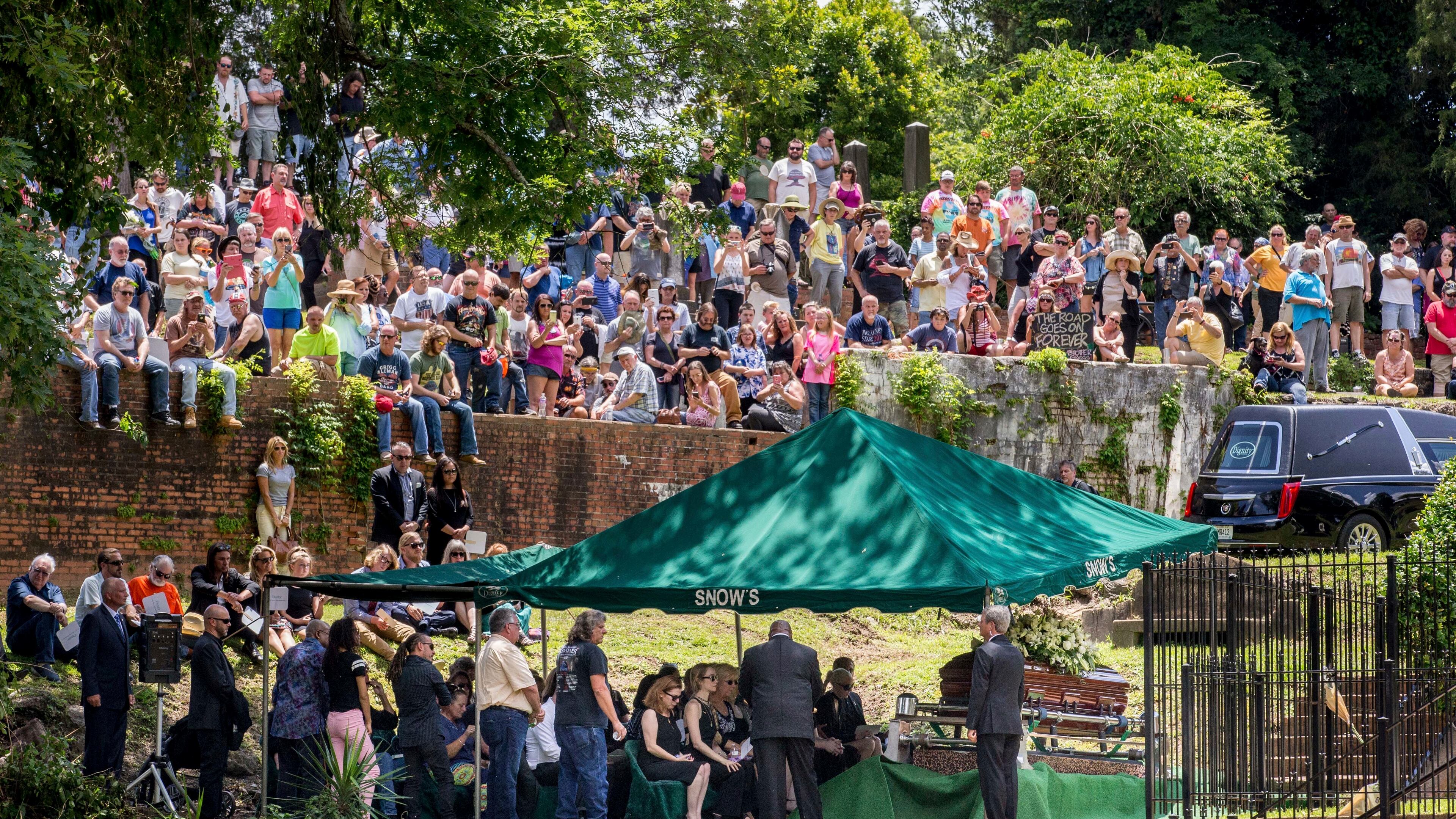 Family, friends and fans attend Gregg Allman's burial at Rose Hill Cemetery, Saturday, June 3, 2017, in Macon, Ga. The family hopes to modify the area and remove the fence separating Gregg from his brother Duane and bandmate Berry Oakley. (AP Photo/Branden Camp)