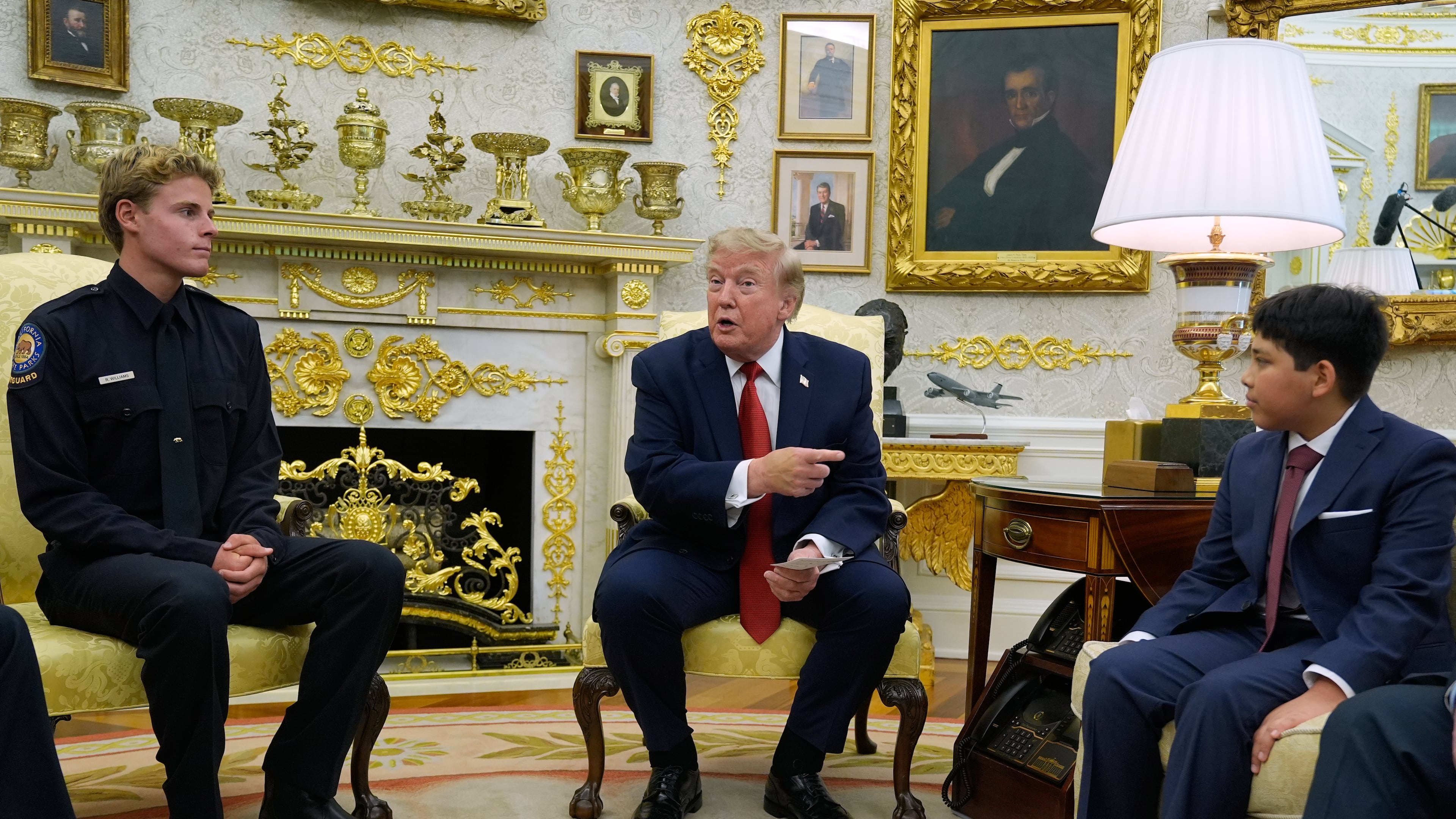 President Donald Trump gestures to Nathaniel Rai, the boy lifeguard Ryder Williams, left, saved as they meet in the Oval Office of the White House, Monday, Aug. 17, 2026, in Washington. (AP Photo/Manuel Balce Ceneta)