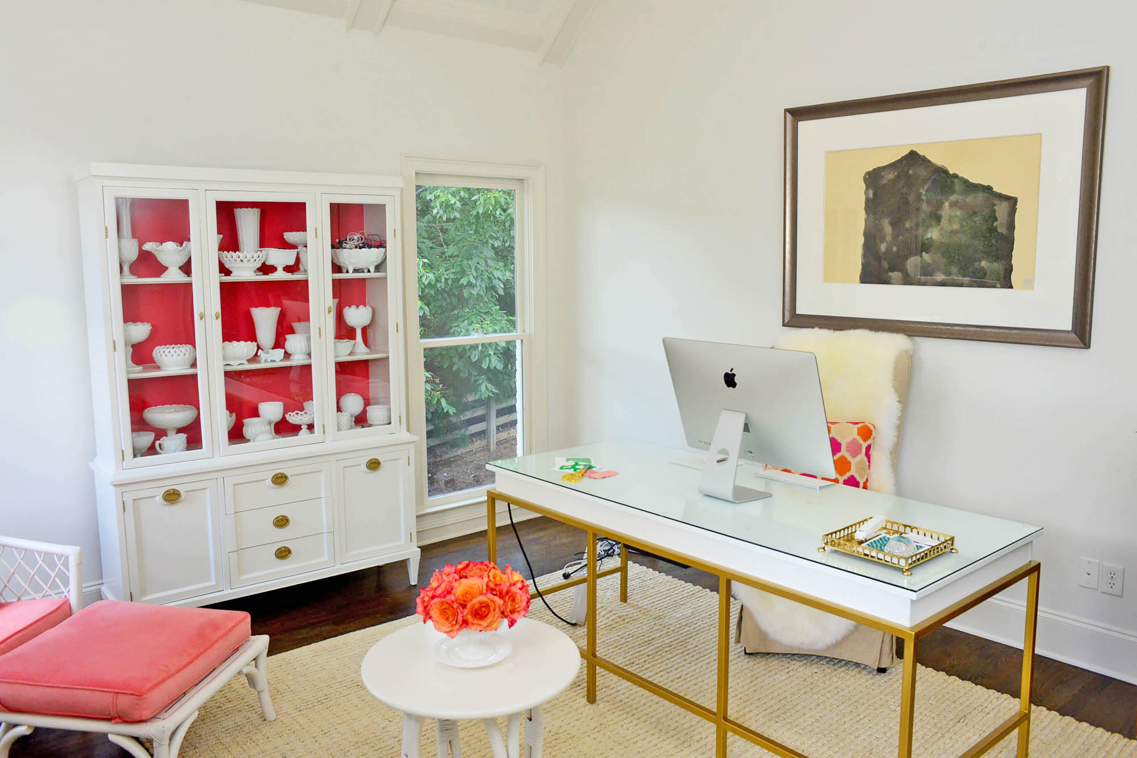A custom midcentury-style white and gold desk, created by Carey Durbin, is a stunning and functional centerpiece in Edee's home office. Edee owns Stephanie Leigh Designs. A fan of creative storage, she often uses her milk glass collection to hold supplies. It's practical and nostalgic, because her grandmother also collected the pieces.