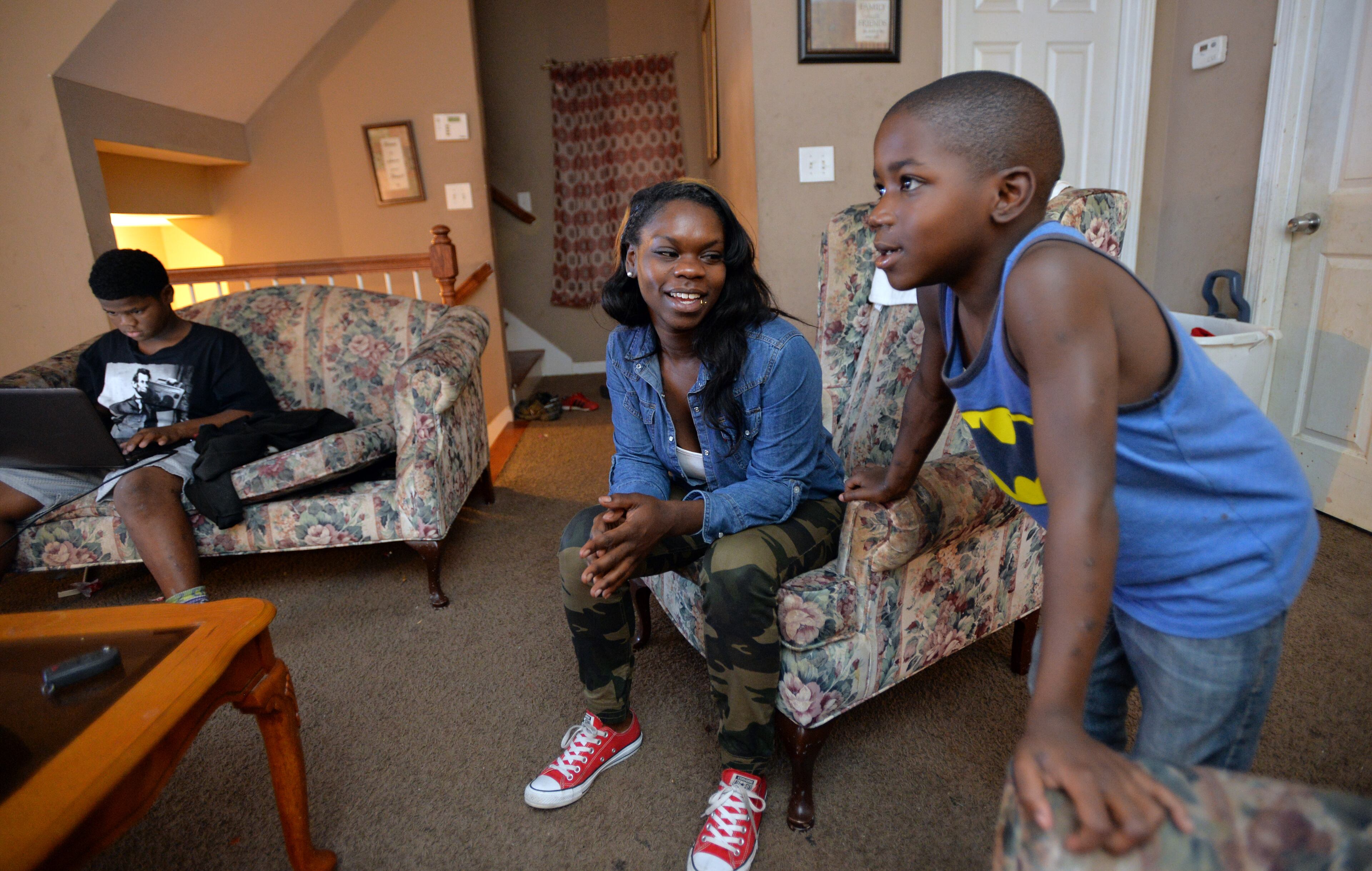Ashley Roberson (center), 23, talks to her youngest brother Damyuss Marshall, 8, as her brother Dazmine Marshall (left), 12, watches a football game from a laptop. HYOSUB SHIN / HSHIN@AJC.COM