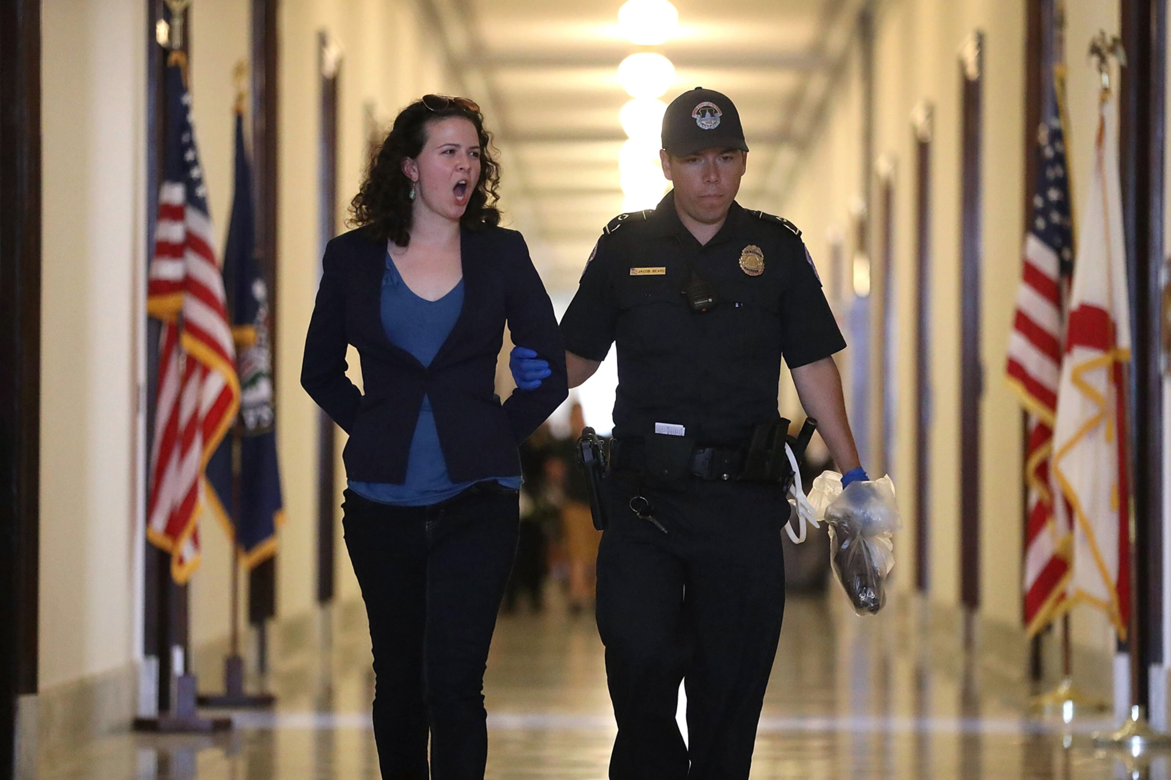 WASHINGTON, DC - JULY 17: A U.S. Capitol Police officer walks with a health care protester that was arrested near the office of Sen. Mitch McConnell (R-KY) in the Russell Senate Office Building on July 17, 2017 in Washington, DC. Capitol Police arrested several protesters at various Senate offices as the protesters asked Senators to vote no on the Better Care Reconciliation Act. (Photo by Joe Raedle/Getty Images)