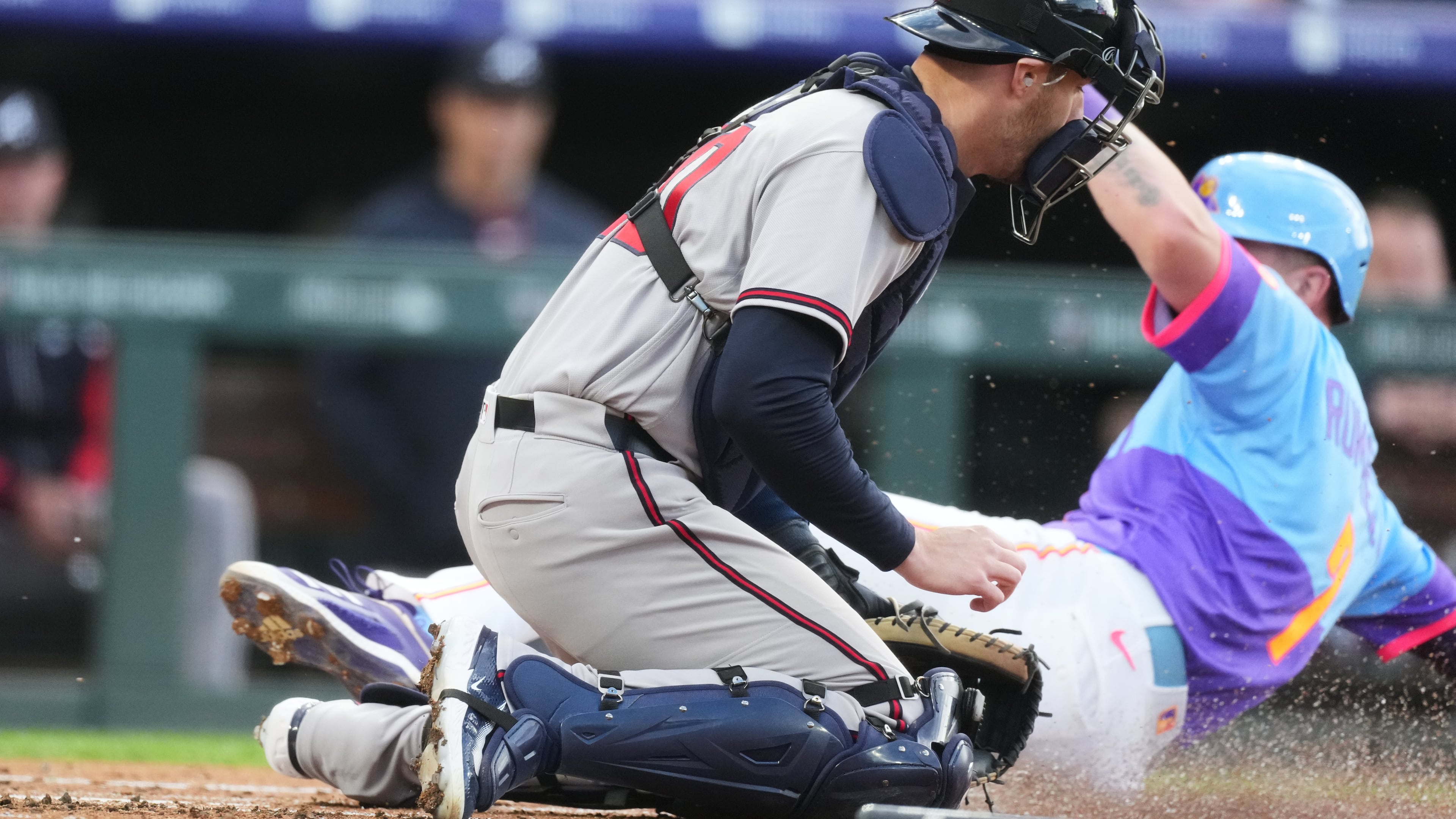 Atlanta Braves catcher Jonah Heim, front, tries to field the throw as Colorado Rockies' TJ Rumfield scores on a ground out by Willi Castro in the first inning of a baseball game Friday, May 1, 2026, in Denver. (AP Photo/David Zalubowski)