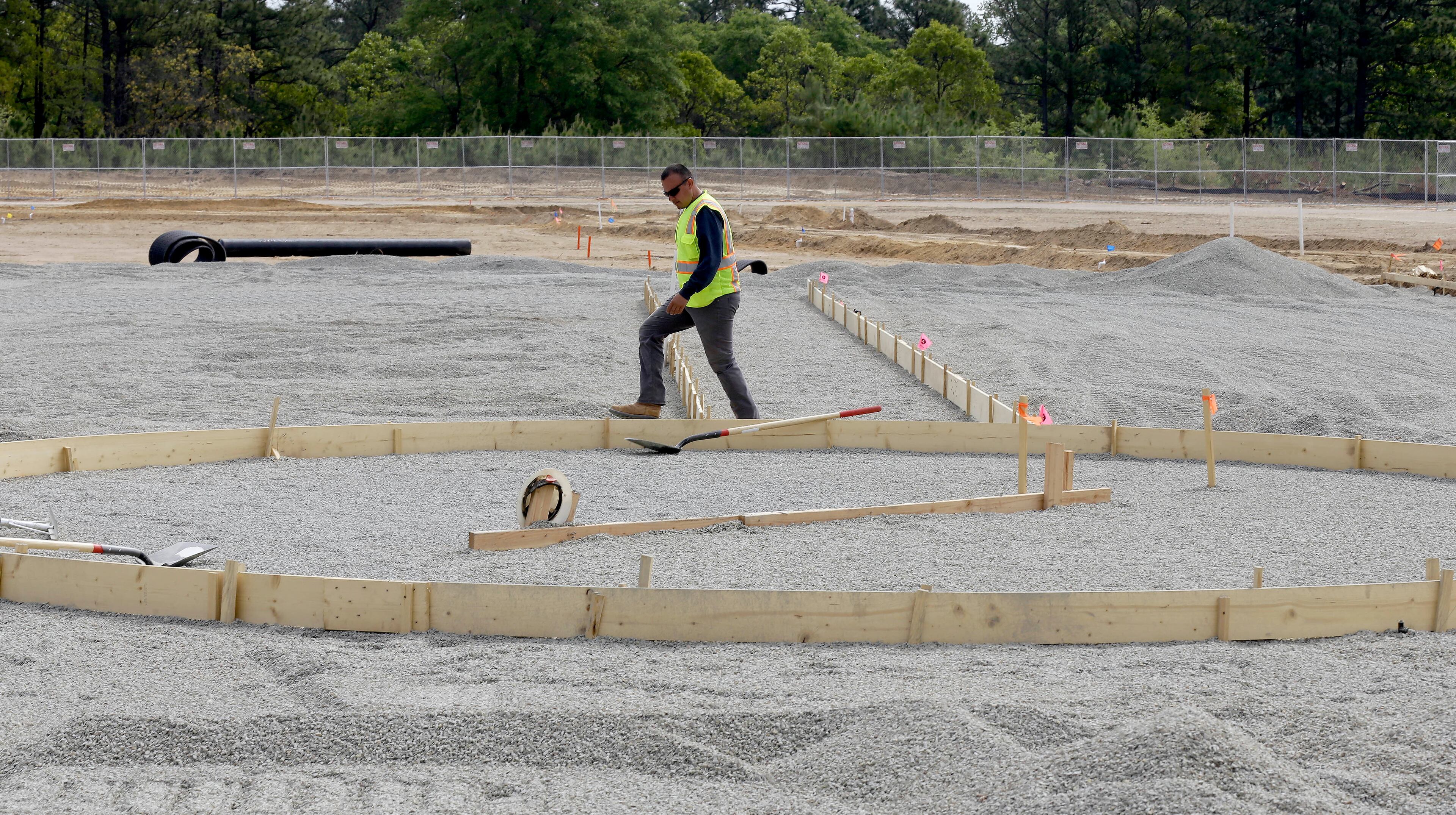 A contractor steps across the path to first base while constructing a baseball field on post at Fort Bragg, N.C. (AP Photo/Gerry Broome)